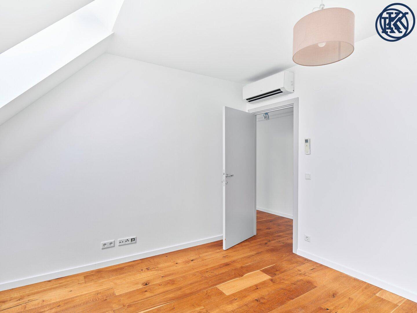 Helles Schlafzimmer mit Holzboden, Klimaanlage und Zugang zu einem begehbaren Kleiderschrank.
