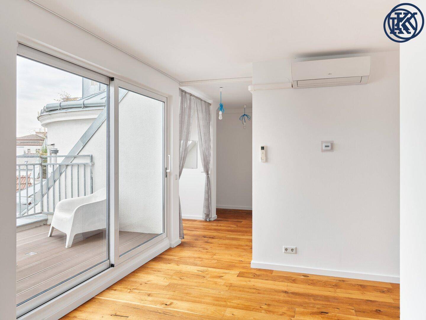 Heller Raum mit Holzboden, Zugang zum Balkon und installierter Klimaanlage.