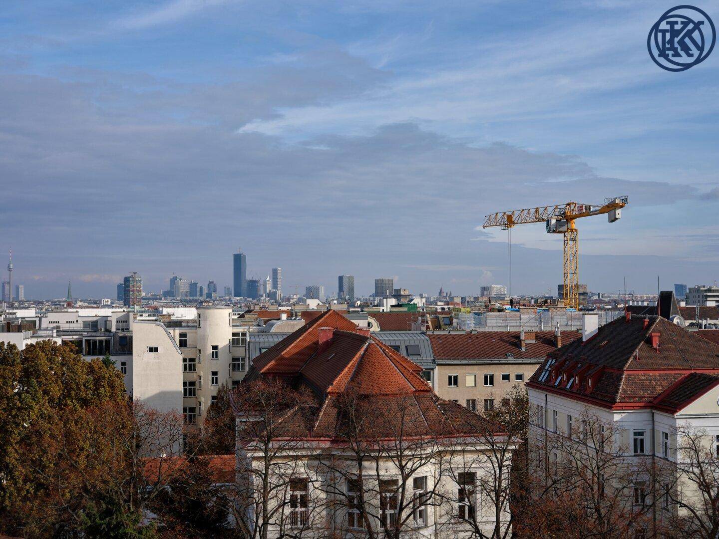 Weitläufiger Blick über die Stadt mit Hochhäusern am Horizont und einem Baukran im Vordergrund.