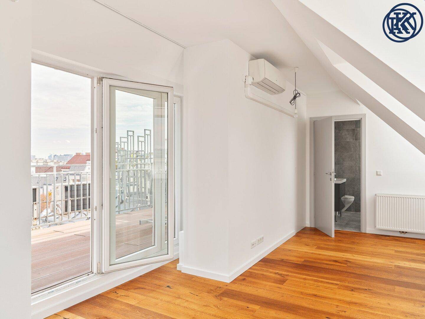 Lichtdurchflutetes Dachzimmer mit Holzboden, Klimaanlage und direktem Zugang zur Dachterrasse.
