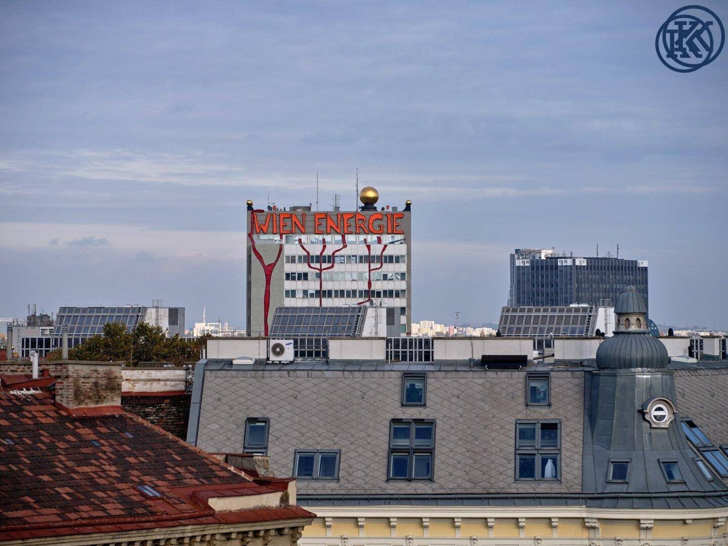 Stadtansicht mit dem Wien Energie Gebäude und umliegenden Dächern unter leicht bewölktem Himmel.