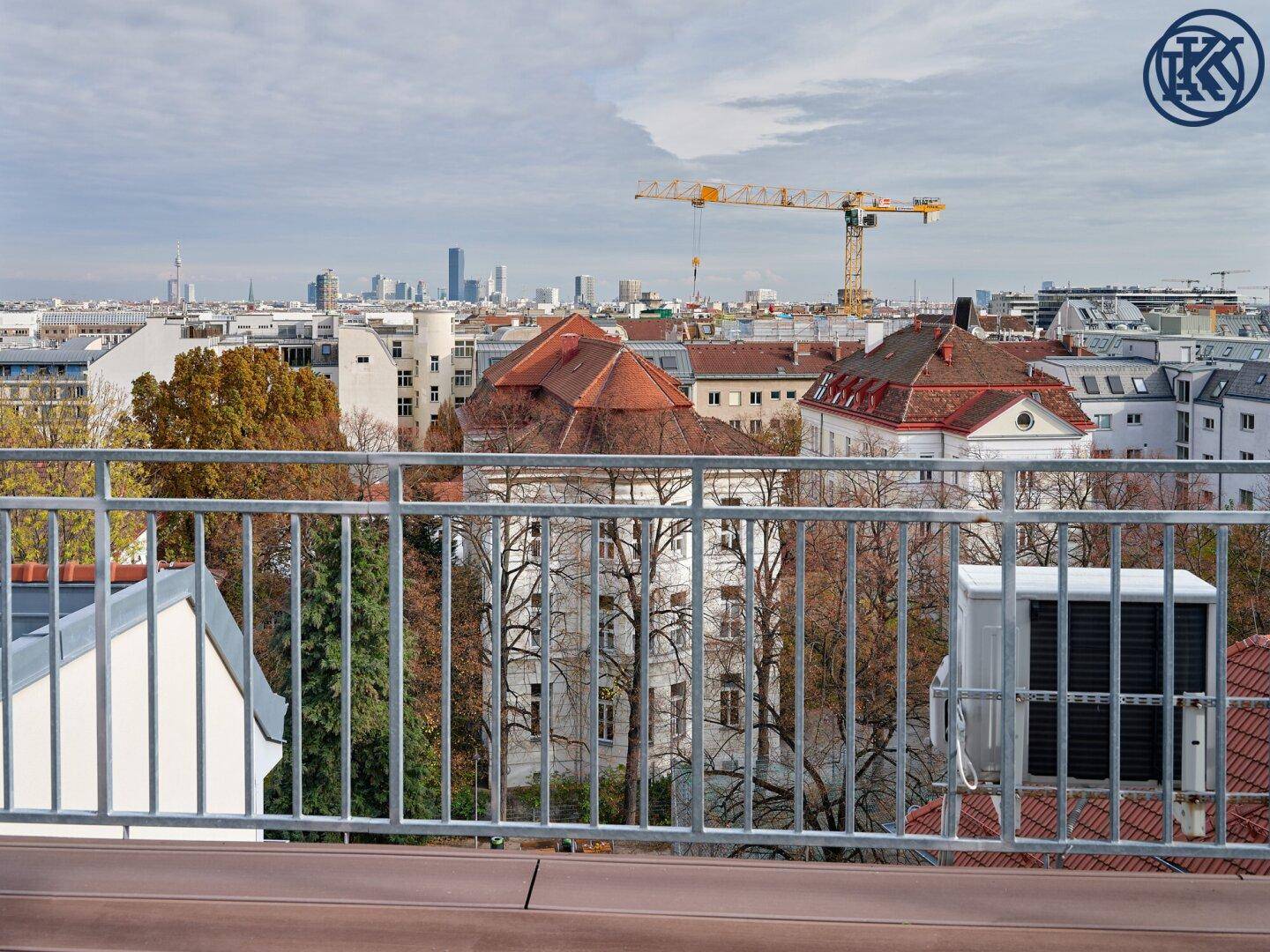 Weitläufiger Stadtblick von einer Dachterrasse mit zahlreichen Gebäuden und einem Baukran.