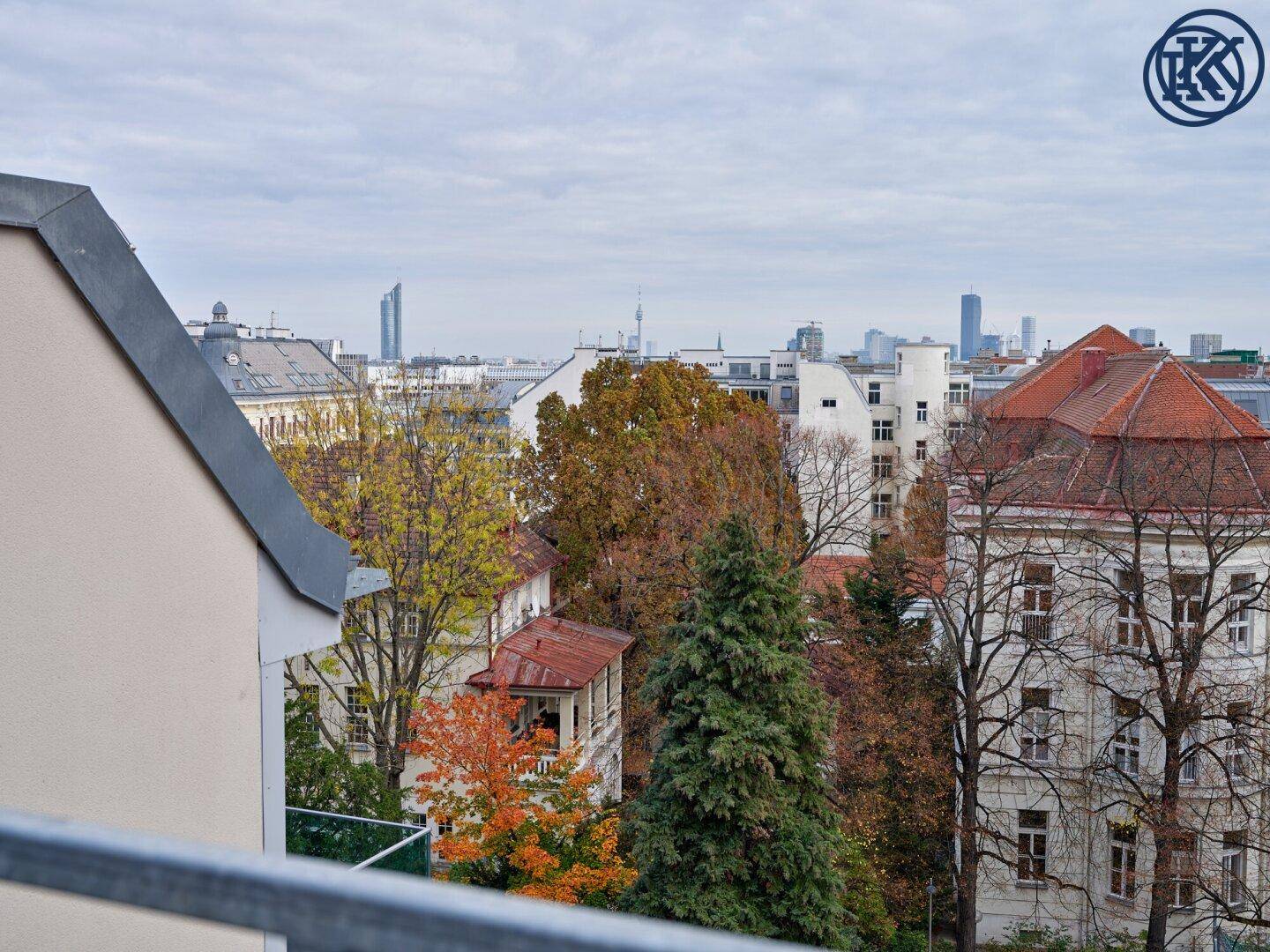 Panoramablick vom Balkon über die Stadt mit grünen Bäumen und historischen Gebäuden.