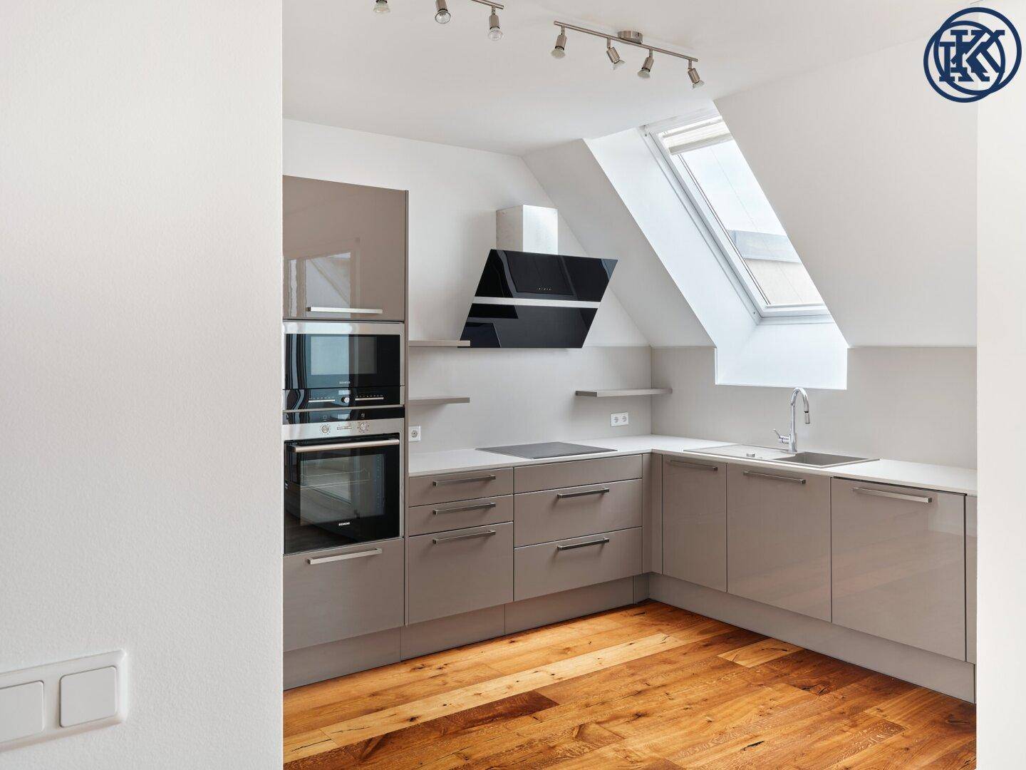 Moderne Einbauküche mit grauen Schränken, Induktionskochfeld und Dachfenster.