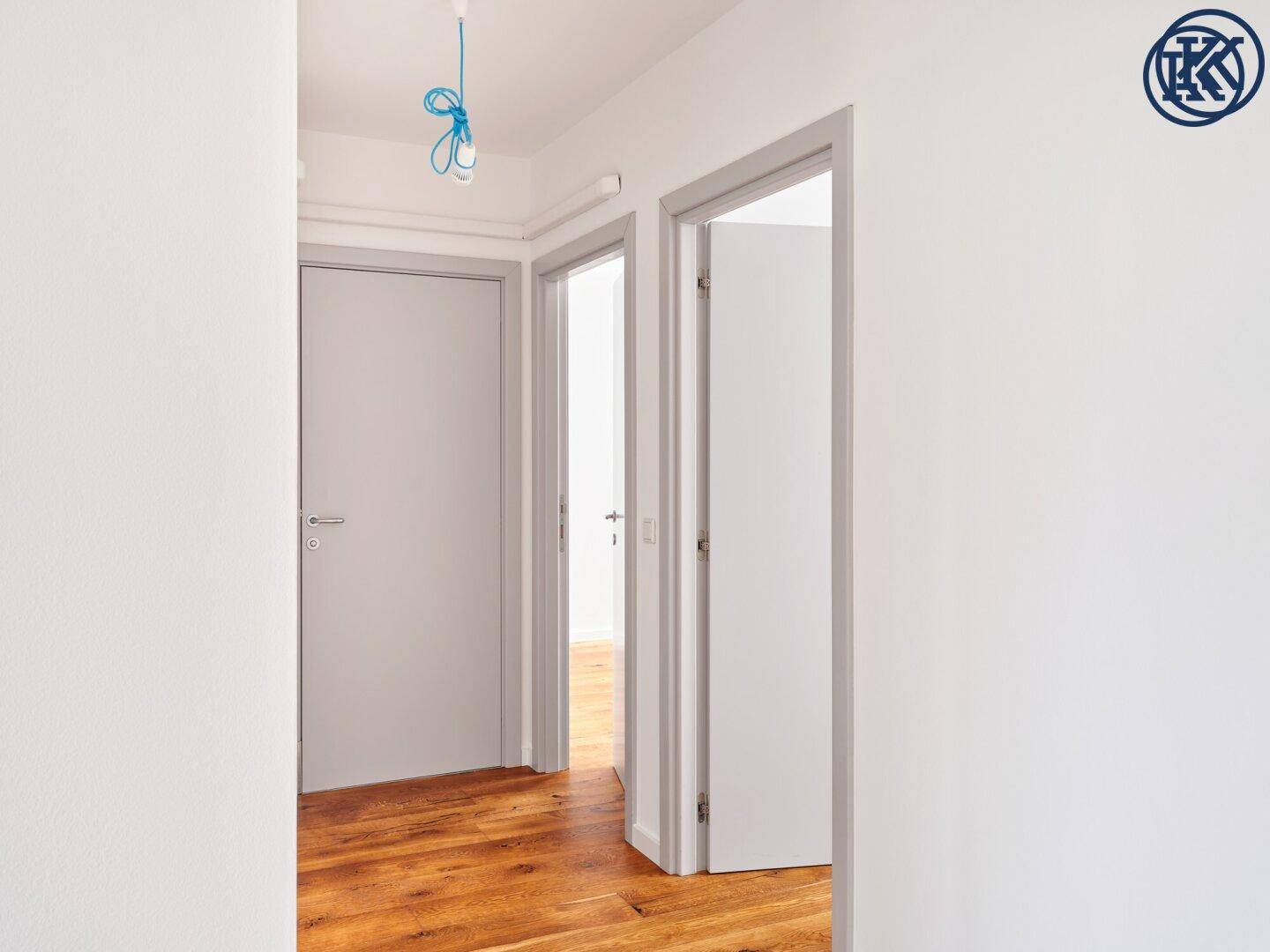 Heller Flur mit Holzboden und mehreren Türen, die zu verschiedenen Zimmern der Wohnung führen.