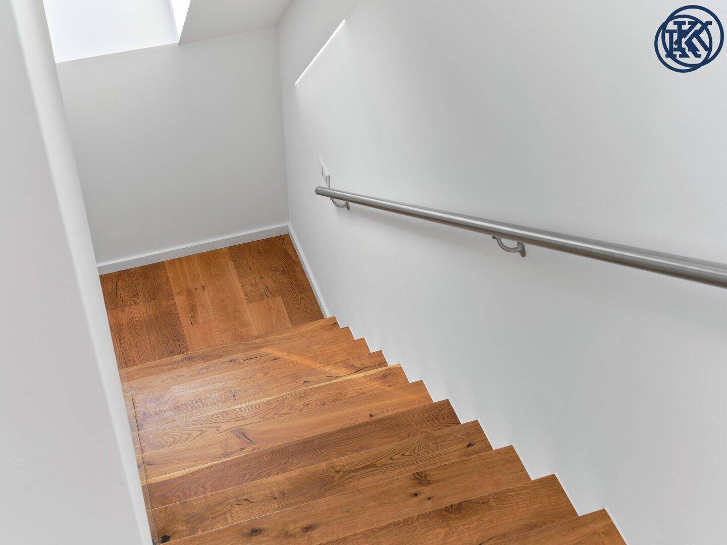 Helle Holztreppe mit schlichtem Metallgeländer, die verschiedene Ebenen des Hauses verbindet.