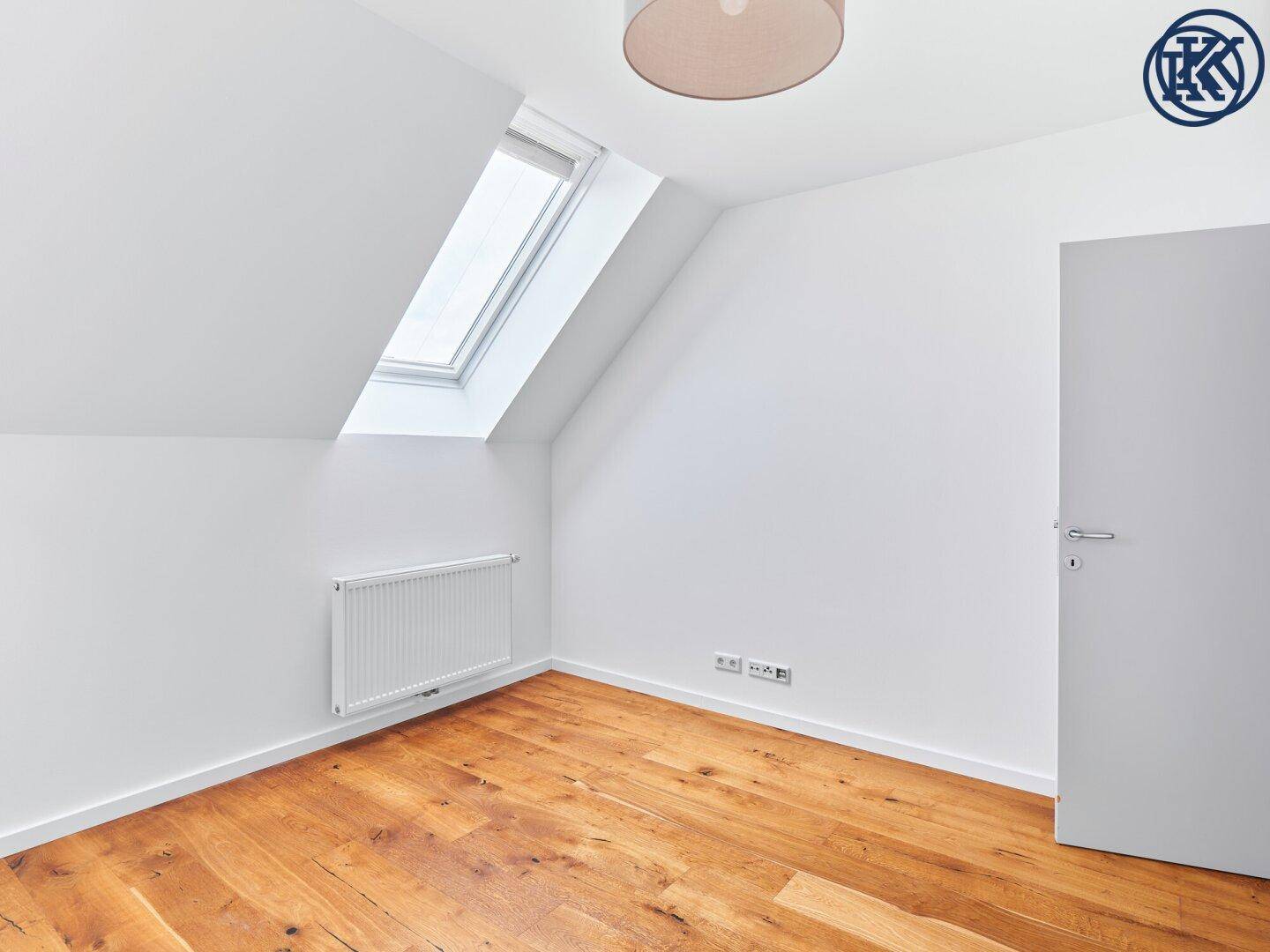 Helles Schlafzimmer im Dachgeschoss mit Holzboden, Heizkörper und einem großen Dachfenster.
