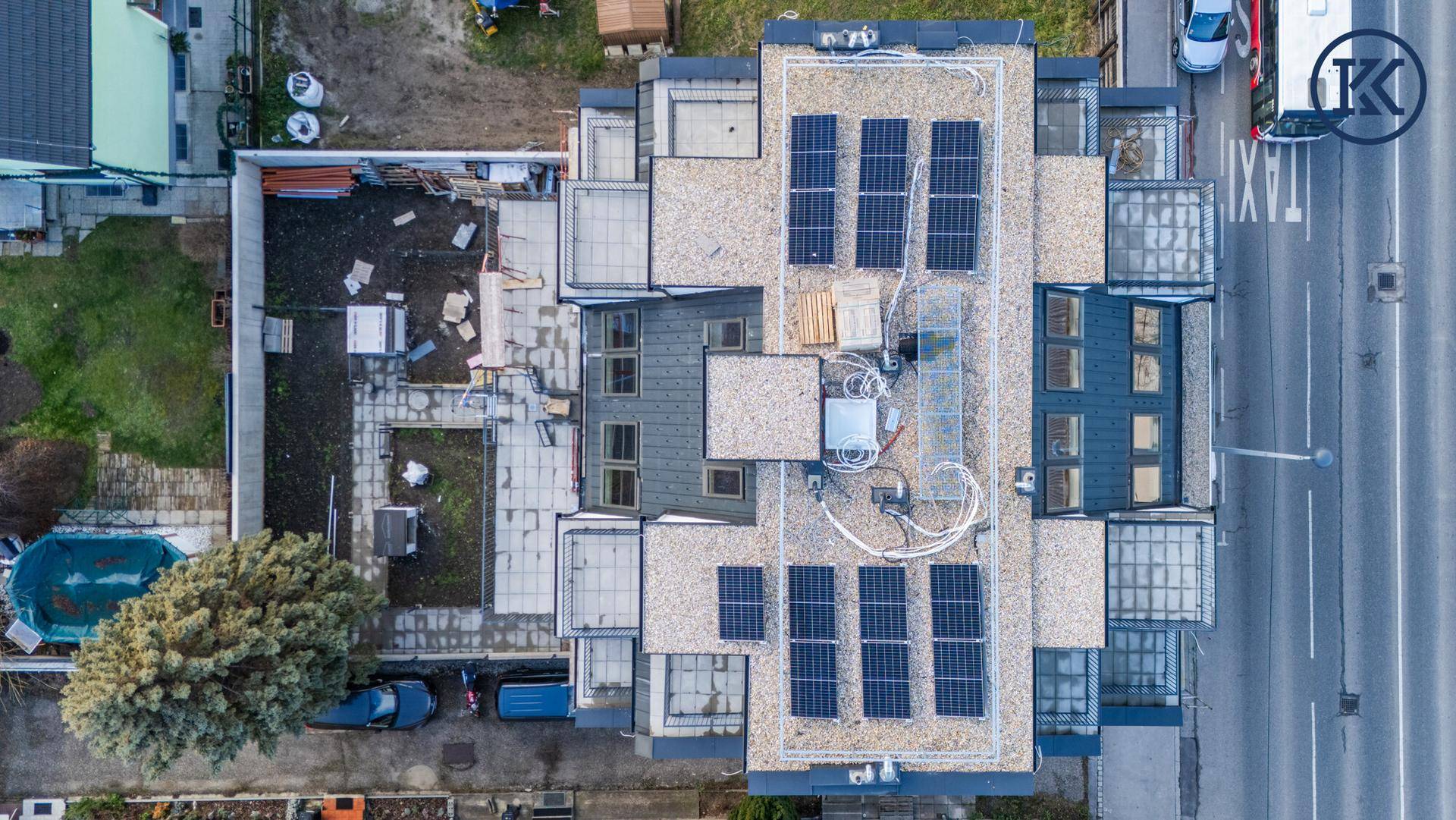 Luftaufnahme des Gebäudedachs mit Photovoltaikanlage und umliegender Bebauung.
