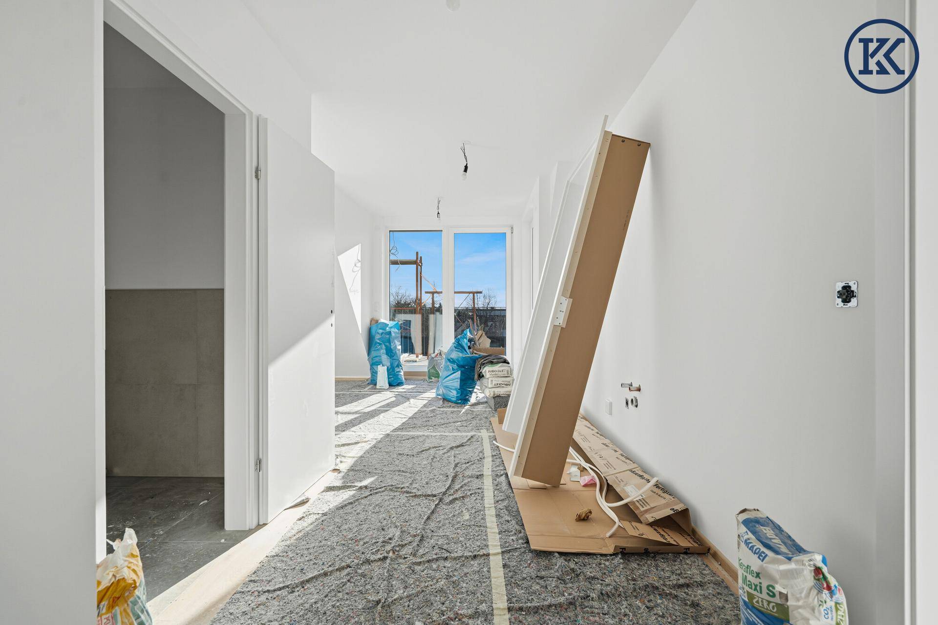 Langer Flur im Rohbau mit viel Tageslicht und Materialien für den weiteren Ausbau.