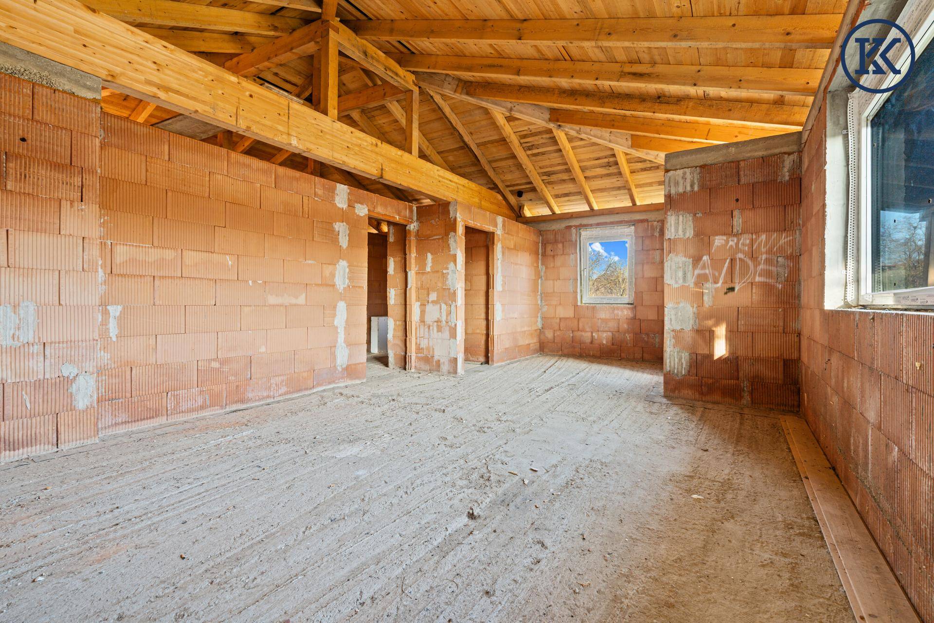 Innenraum im Rohbau mit Ziegelwänden und offener Holzkonstruktion des Daches, viel Potenzial.