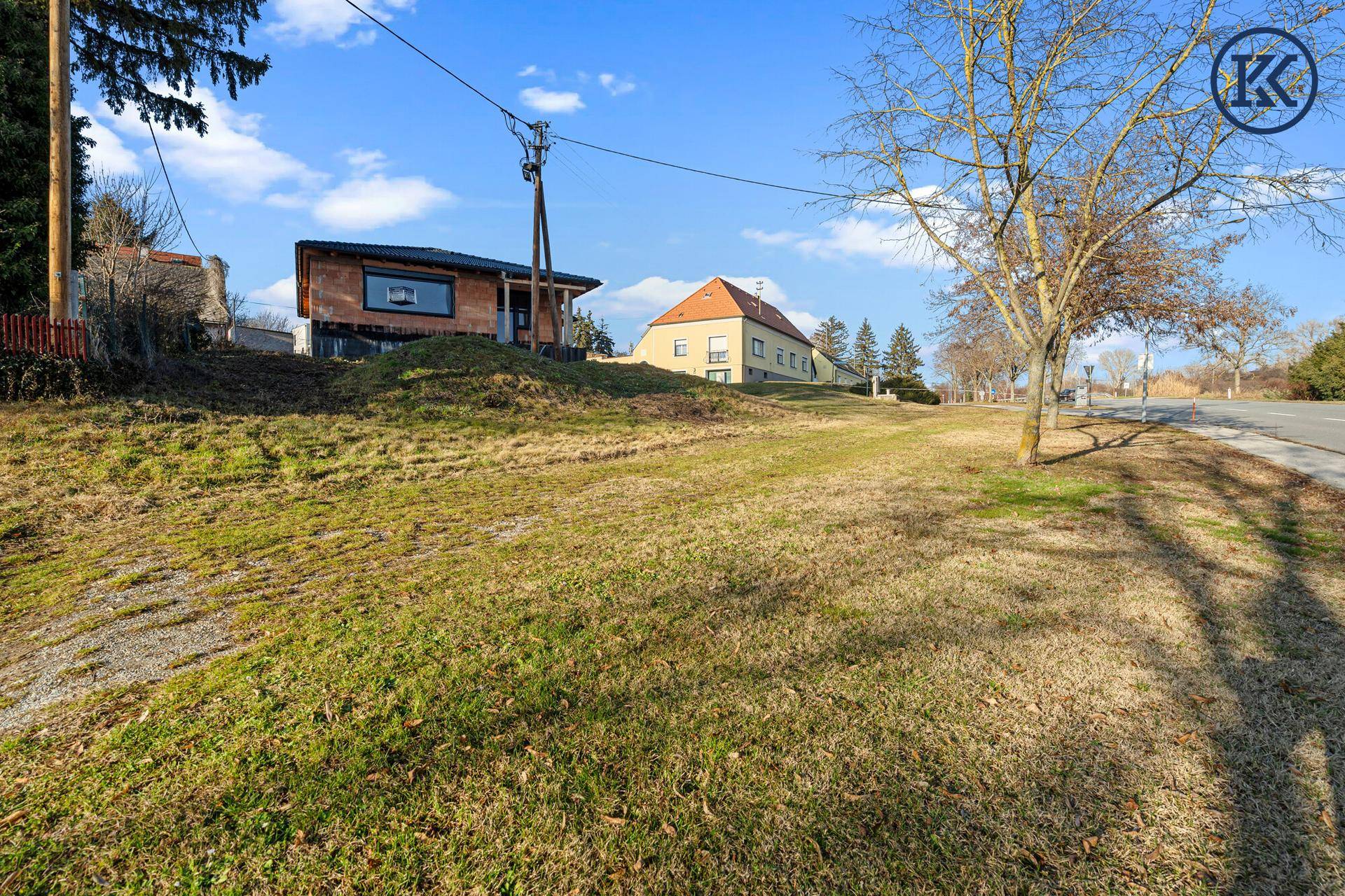 Weitläufige Ansicht des Grundstücks mit dem Rohbauhaus und der umliegenden grünen Landschaft.