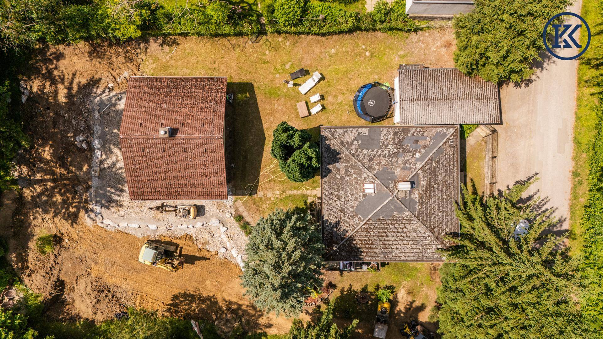 Luftaufnahme des Grundstücks mit zwei Häusern, Baustelle und umgebender Natur.