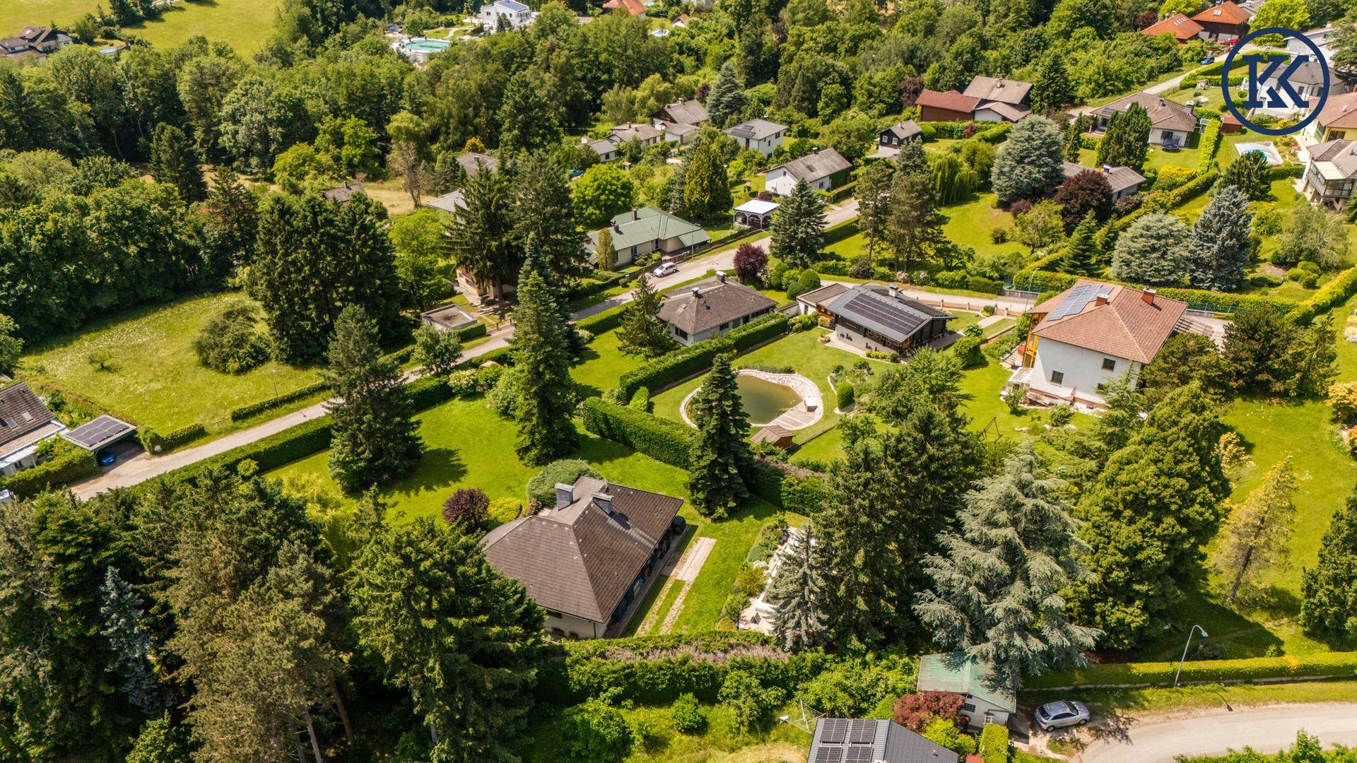 Panoramische Luftaufnahme einer grünen Wohnsiedlung mit Häusern und Gärten.