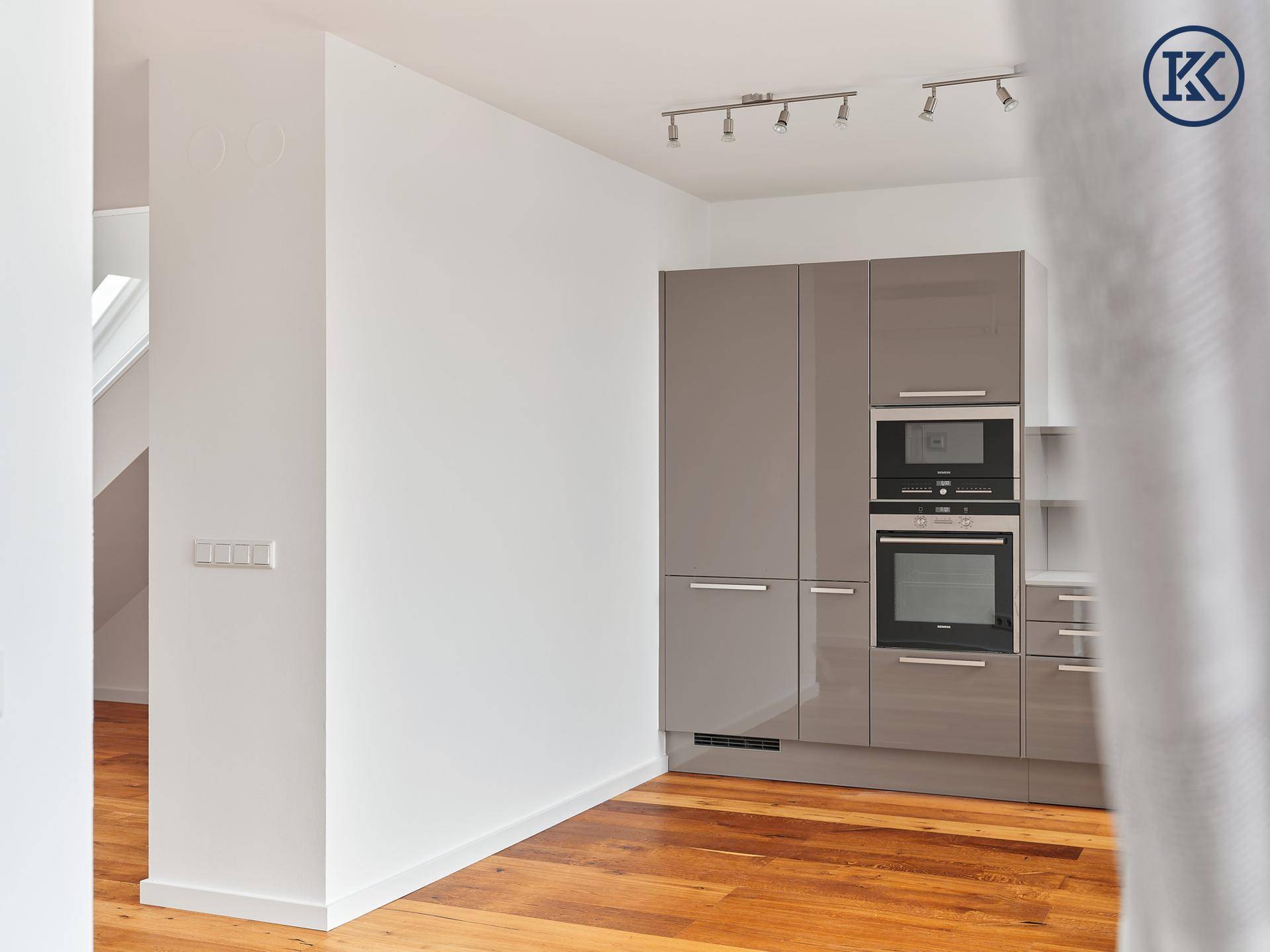 Moderne Einbauküche mit grauen Hochglanzfronten und integrierten Siemens-Geräten.