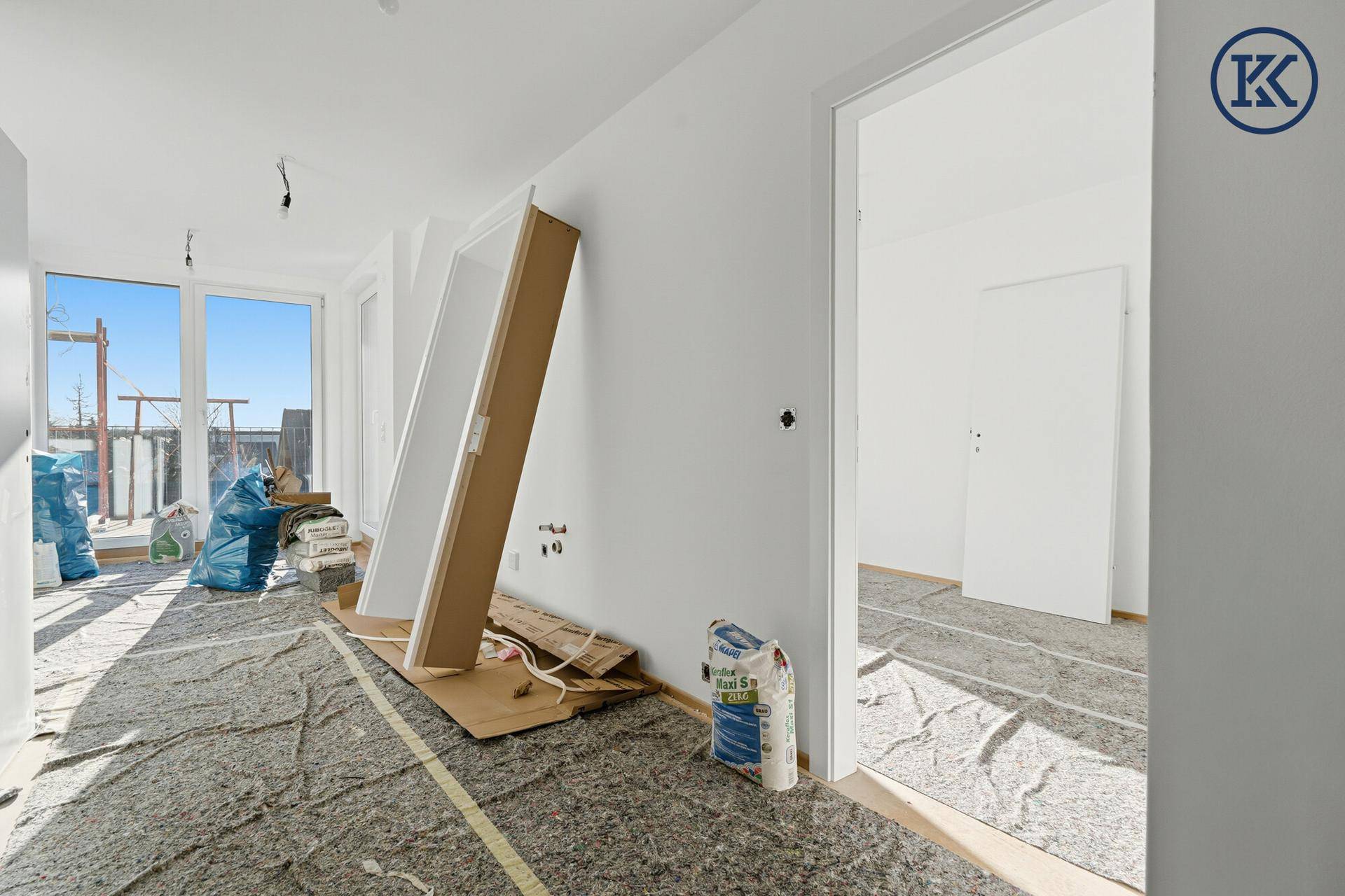 Heller Innenraum im Rohbau mit großen Fenstern und viel Tageslicht, bereit für die Fertigstellung.