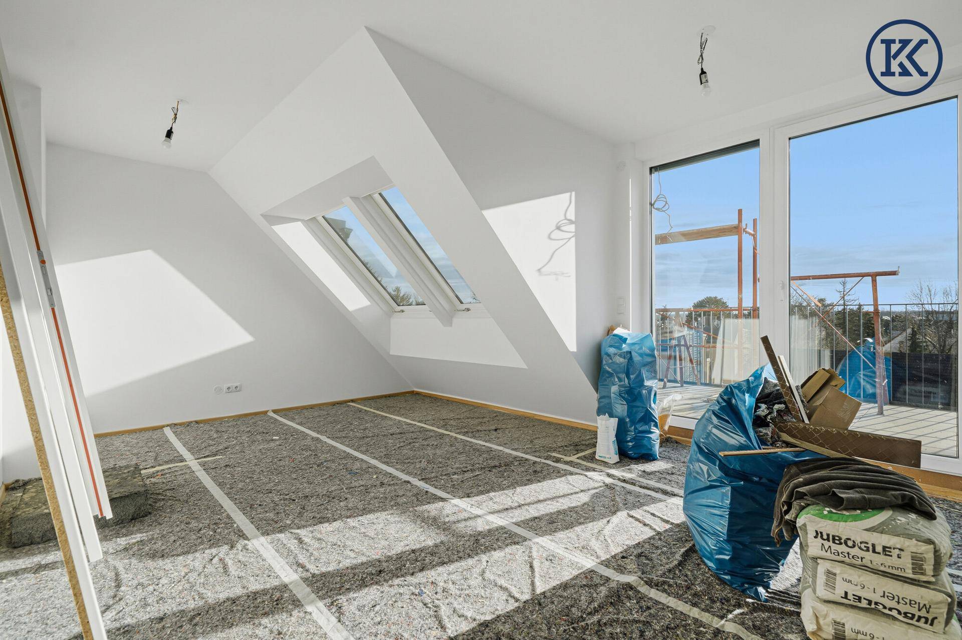 Heller Raum im Dachgeschoss mit großen Fenstern, Dachschrägen und viel Tageslicht.