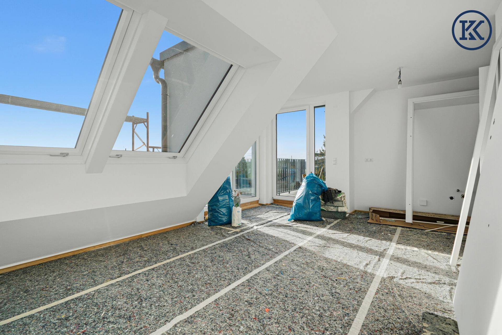 Lichtdurchfluteter Raum im Dachgeschoss mit Dachfenstern und Zugang zu einem Balkon.