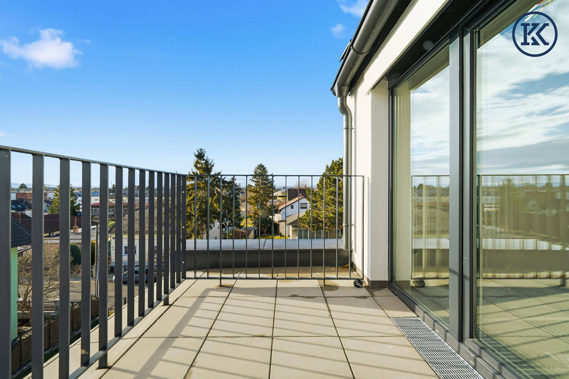 Geräumiger Balkon mit Fliesenboden und Metallgeländer, bietet einen weiten Blick.