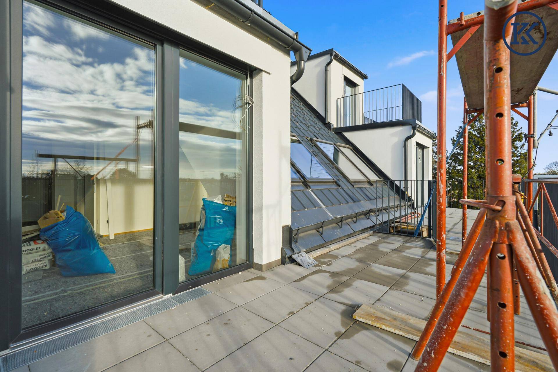 Großer Balkon mit Fliesenboden und Blick auf die Umgebung, noch mit Baugerüst.