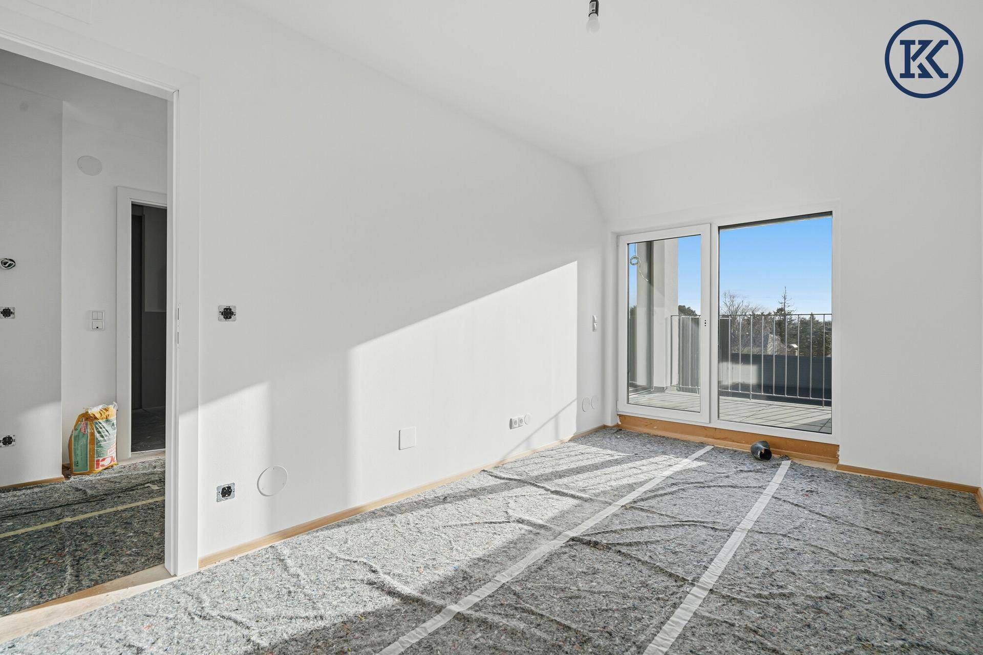Lichtdurchflutetes Schlafzimmer im Rohbau mit Balkonzugang und sonnigem Ambiente.