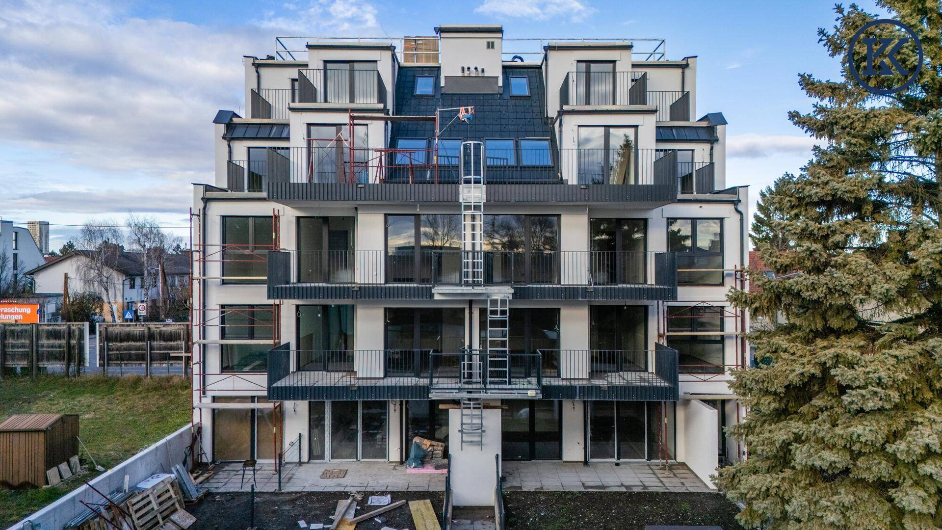 Rückansicht eines modernen Wohngebäudes im Bau, mit Terrassen und Gartenbereich.
