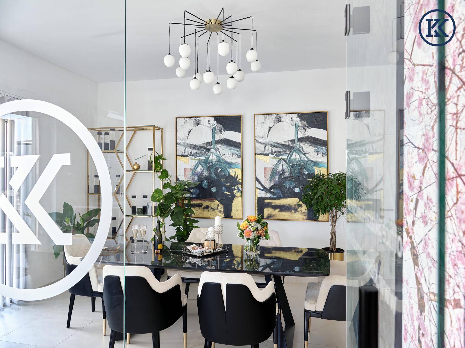 Blick in den Besprechungsraum durch eine Glaswand, mit elegantem Tisch, Stühlen und einem modernen Kronleuchter.