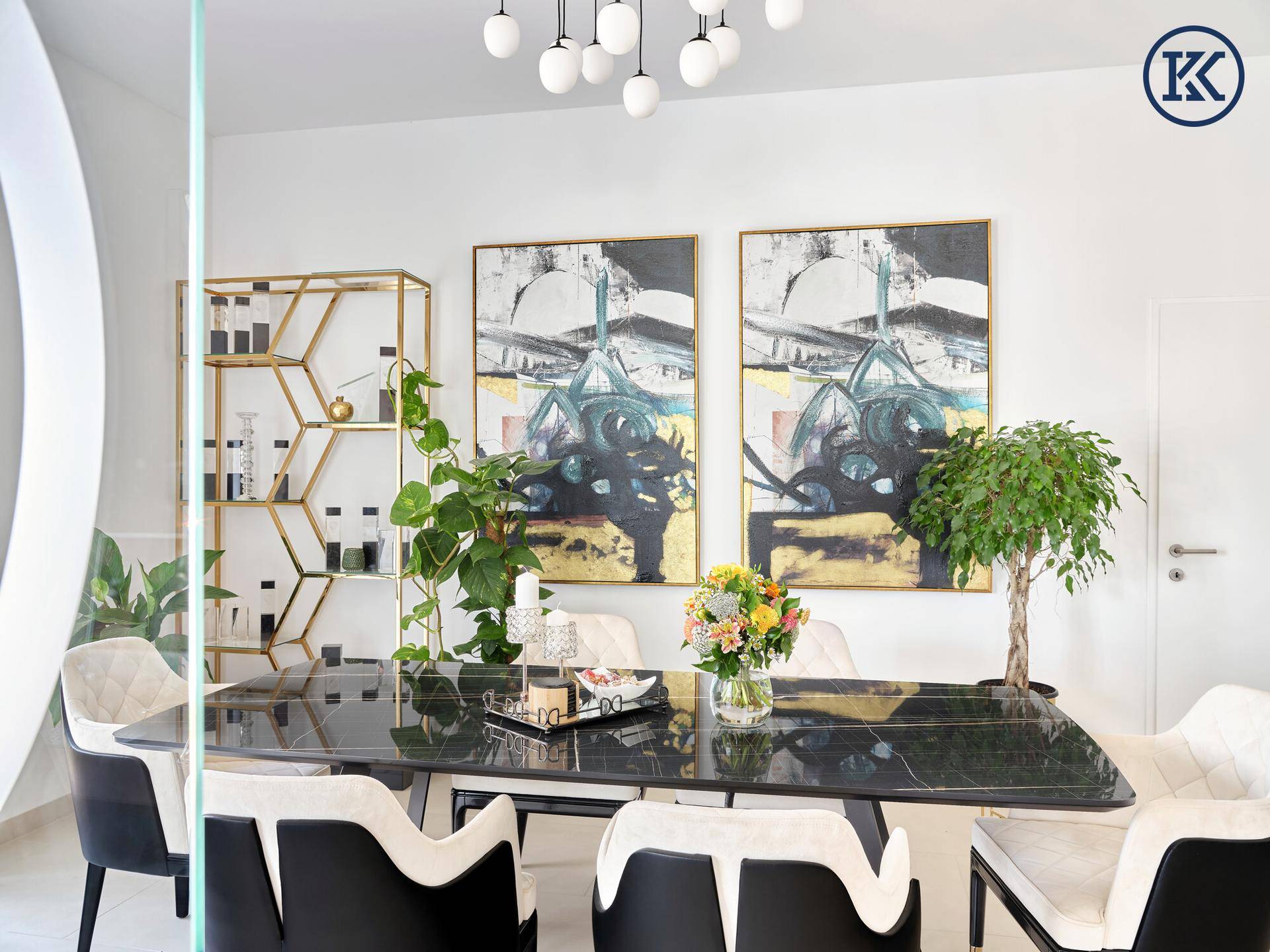 Eleganter Besprechungsraum mit schwarzem Marmortisch, modernen Stühlen, Pflanzen und abstrakten Kunstwerken.