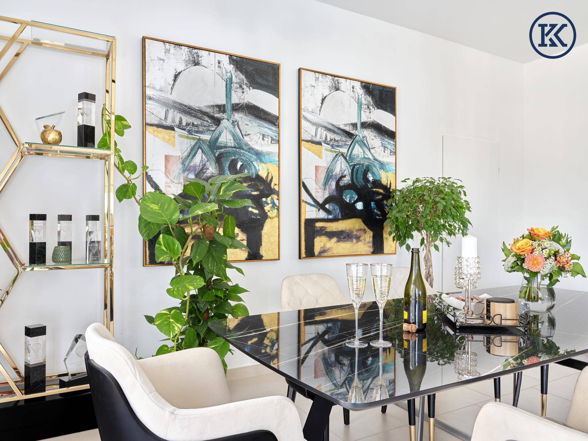 Besprechungstisch mit Sekt, Blumen und einem dekorativen Regal im Hintergrund, in einem hellen Raum.
