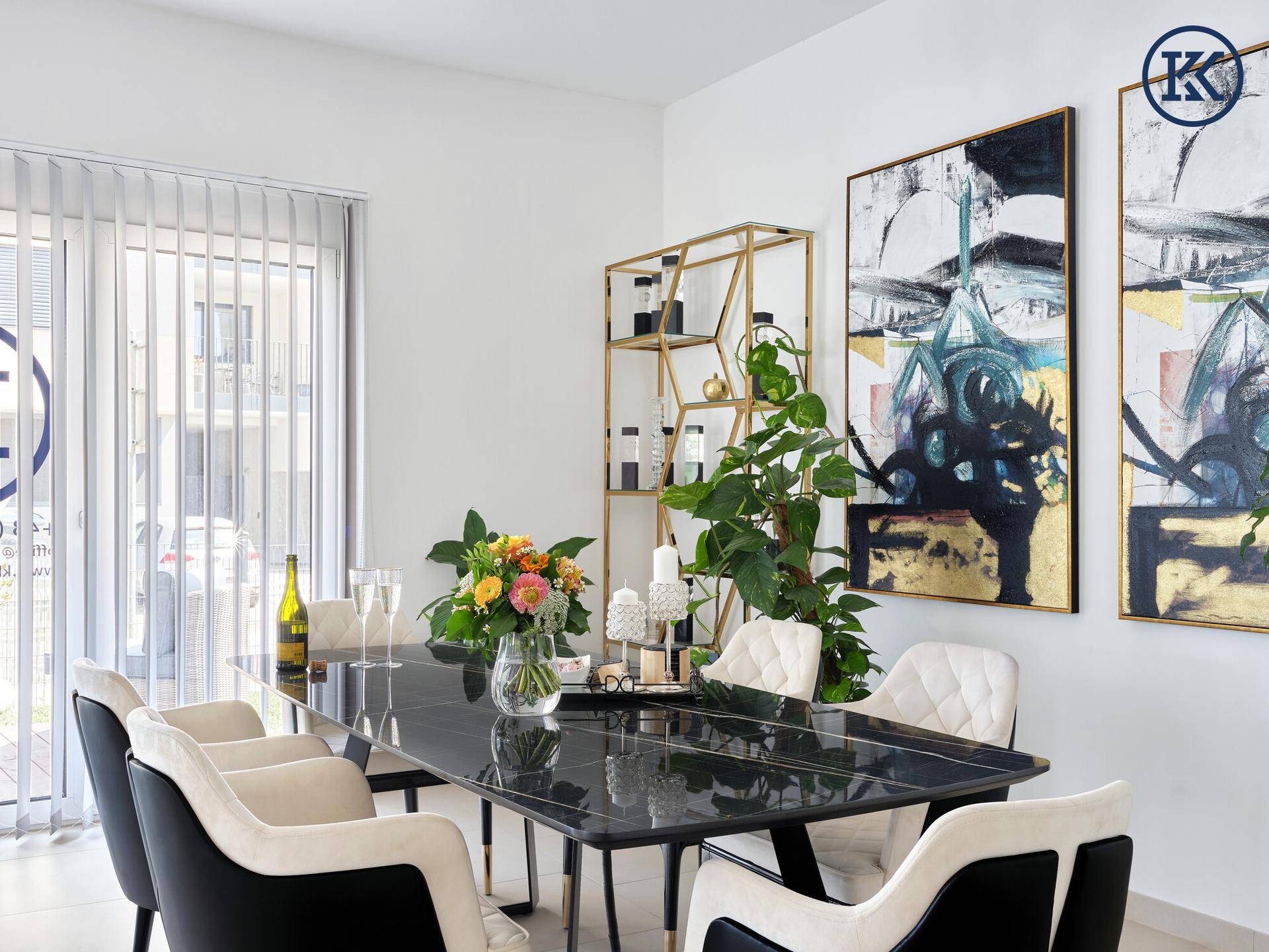 Heller Besprechungsraum mit großem Tisch, bequemen Stühlen, Pflanzen und Kunstwerken, mit Fensterjalousien.