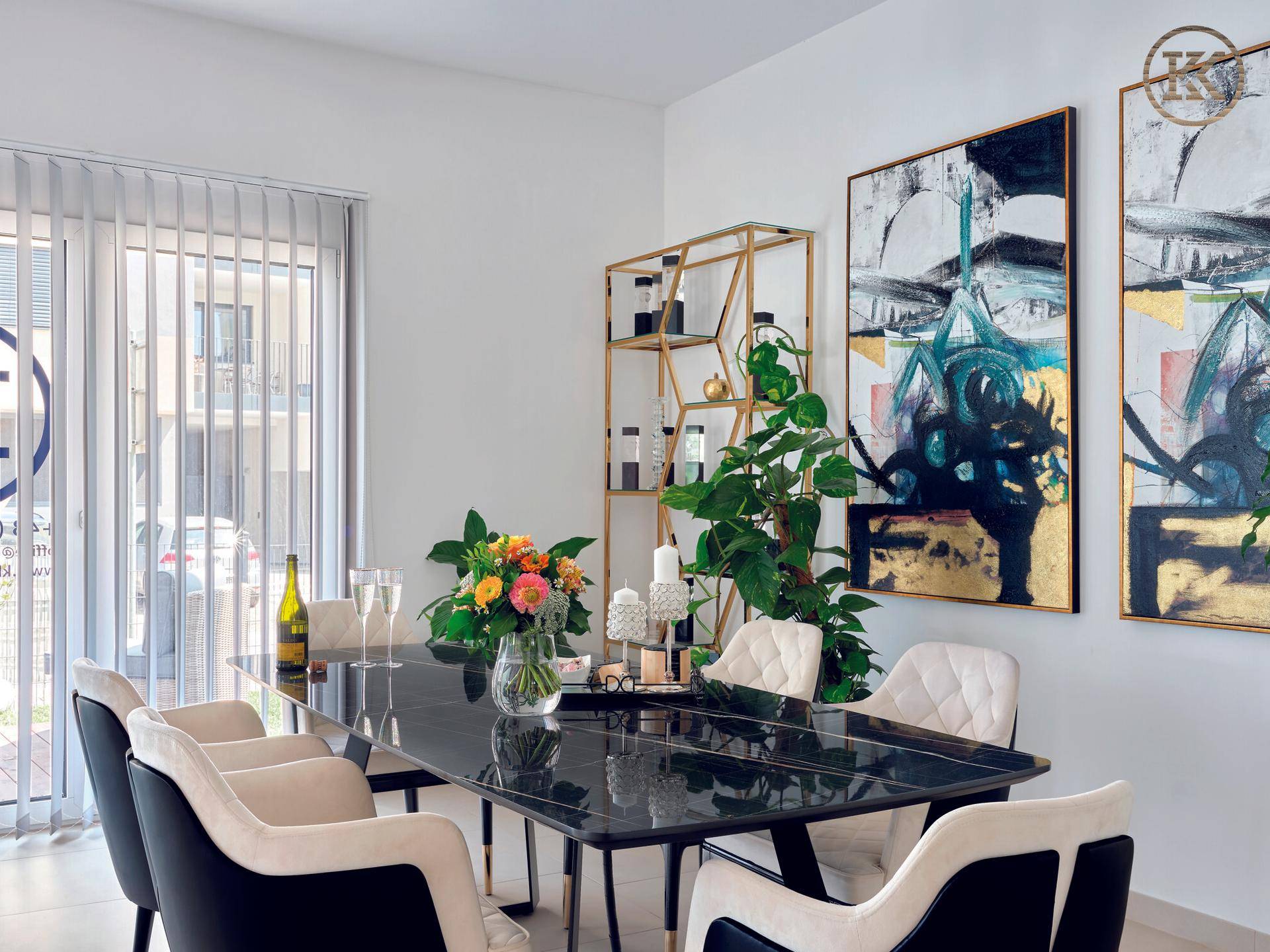 Heller Besprechungsraum mit großem Tisch, bequemen Stühlen, Pflanzen und Kunstwerken, mit Fensterjalousien.