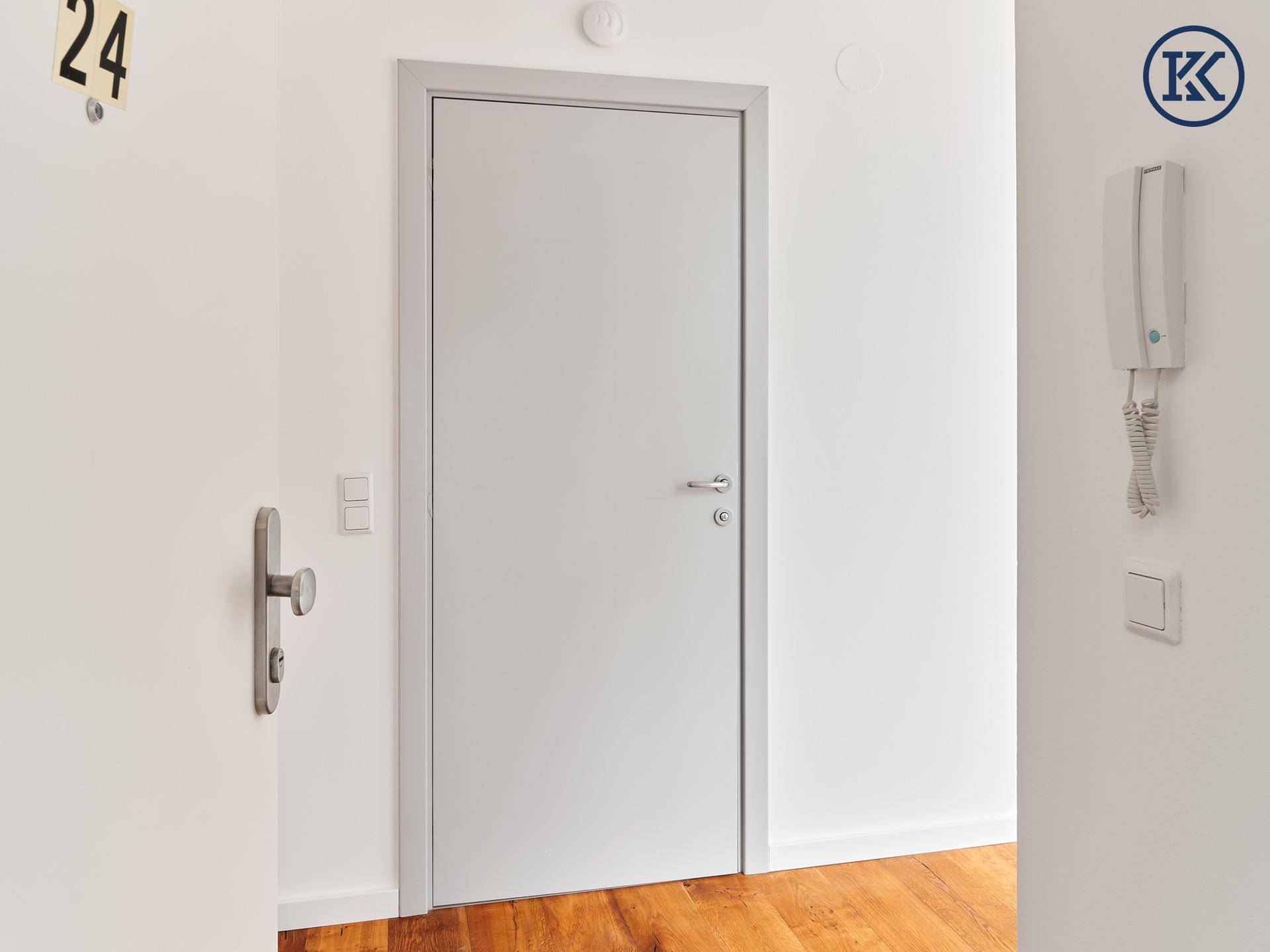 Detailansicht des Wohnungseingangs mit Tür, Gegensprechanlage und Schalter.