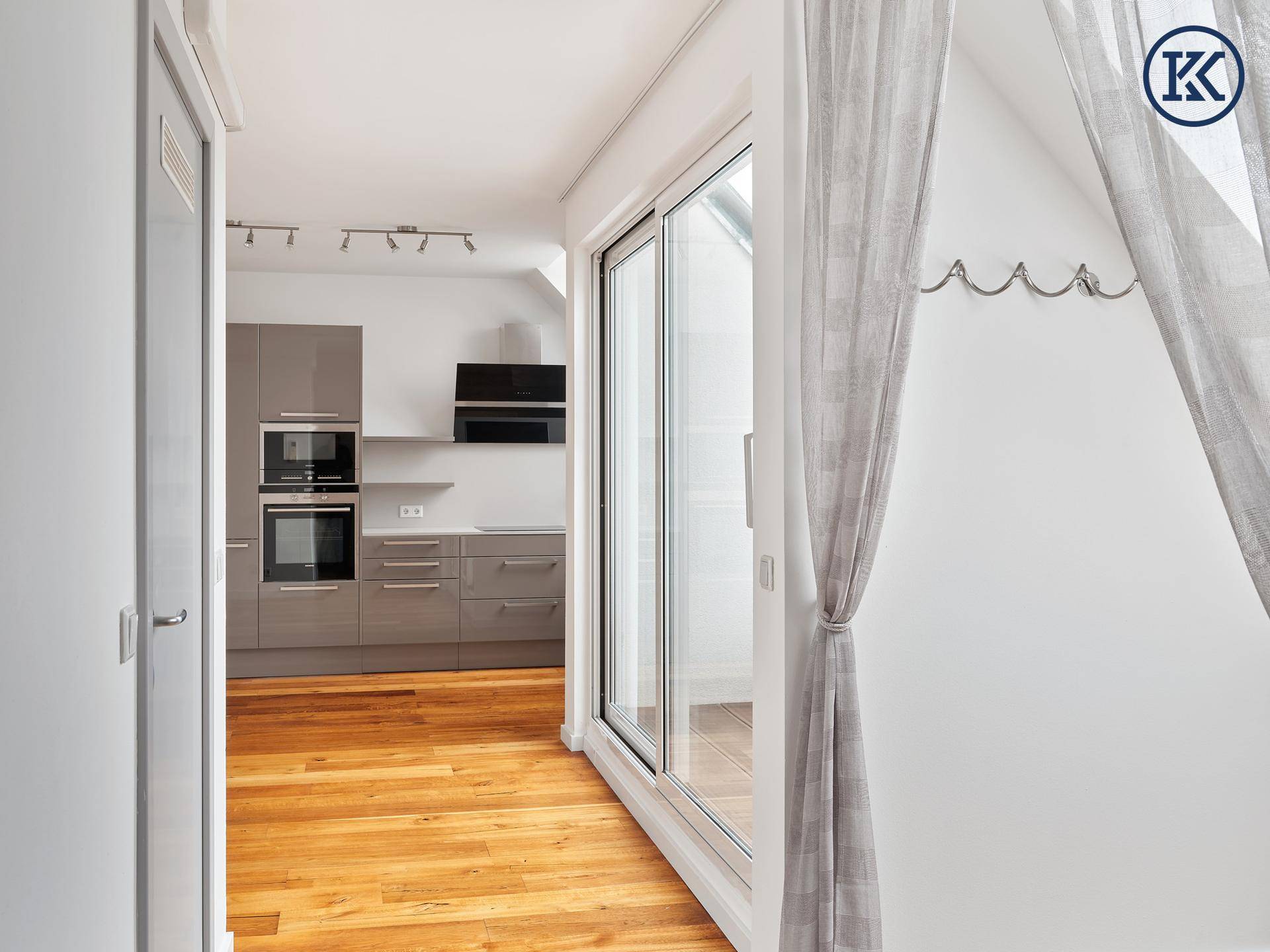 Offener Wohnbereich mit Küche, Holzboden und einem großen Dachfenster.