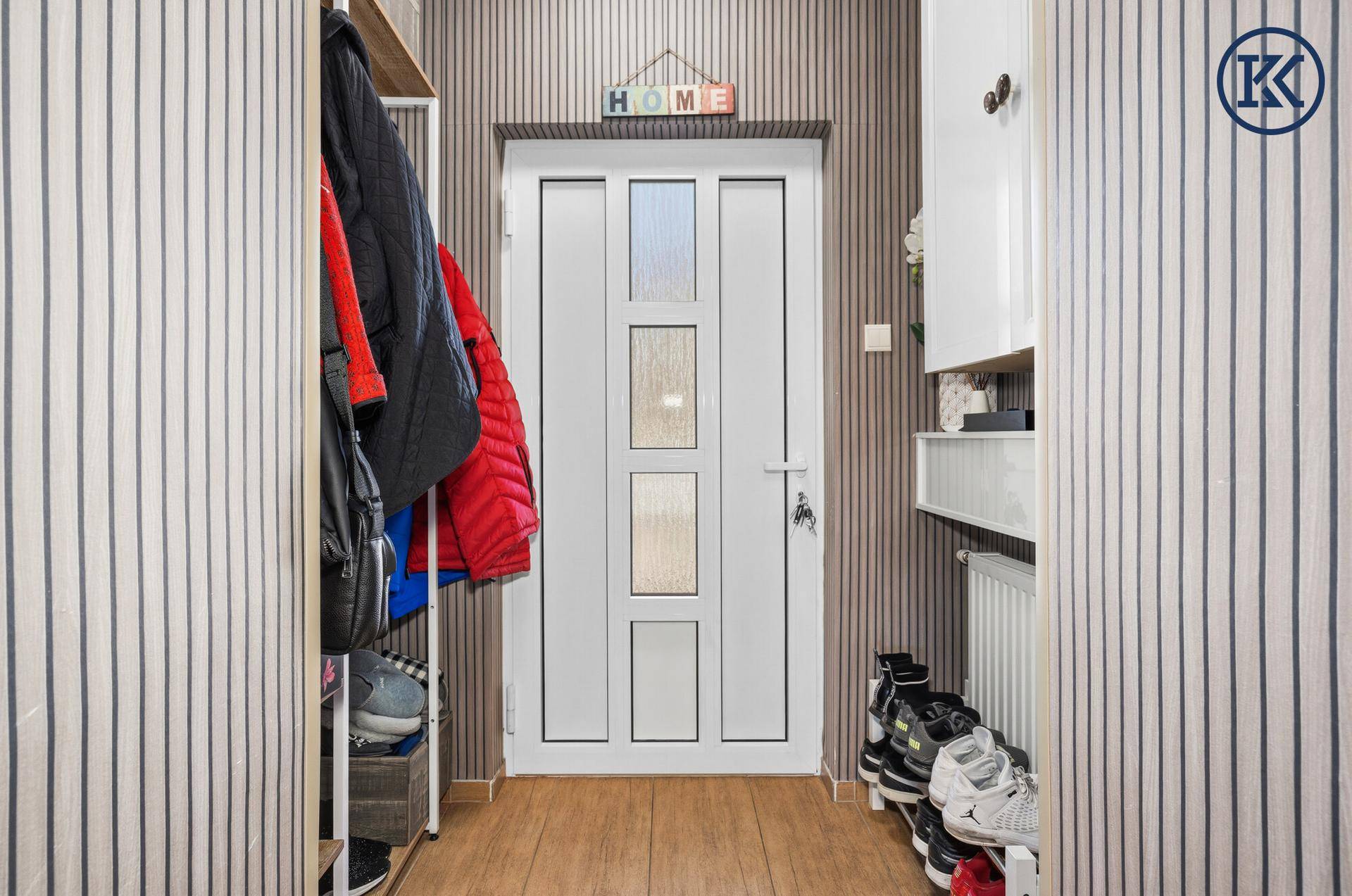 Heller Eingangsbereich mit gestreiften Tapeten und praktischer Garderobe für Schuhe und Jacken.