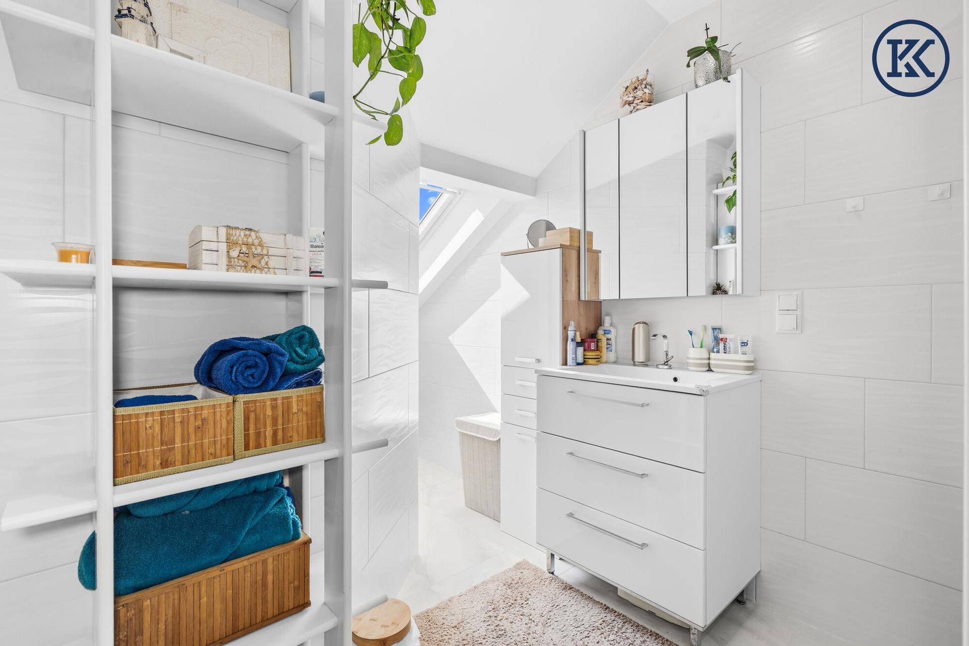 Modernes Badezimmer im Dachgeschoss mit Dusche, Waschbecken und viel Stauraum.