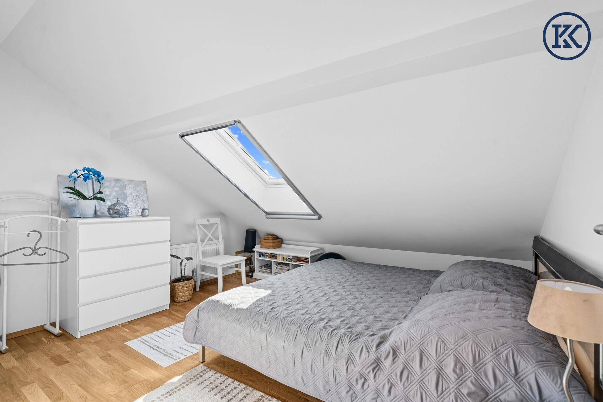 Gemütliches Schlafzimmer im Dachgeschoss mit Doppelbett, Holzfußboden und Dachfenster.