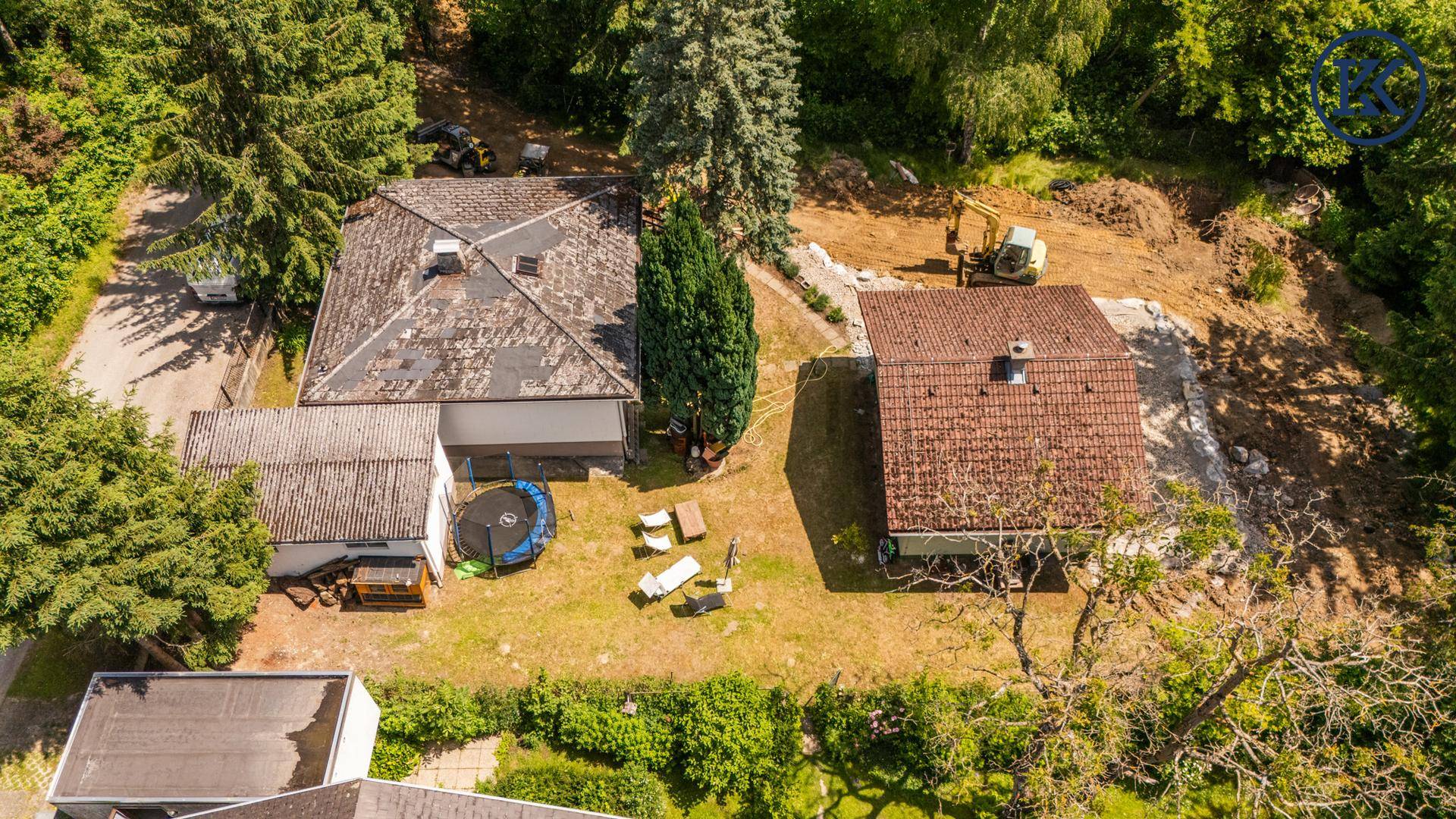 Überblick über das Anwesen mit zwei Häusern, Gartenbereich und angrenzender Baustelle.
