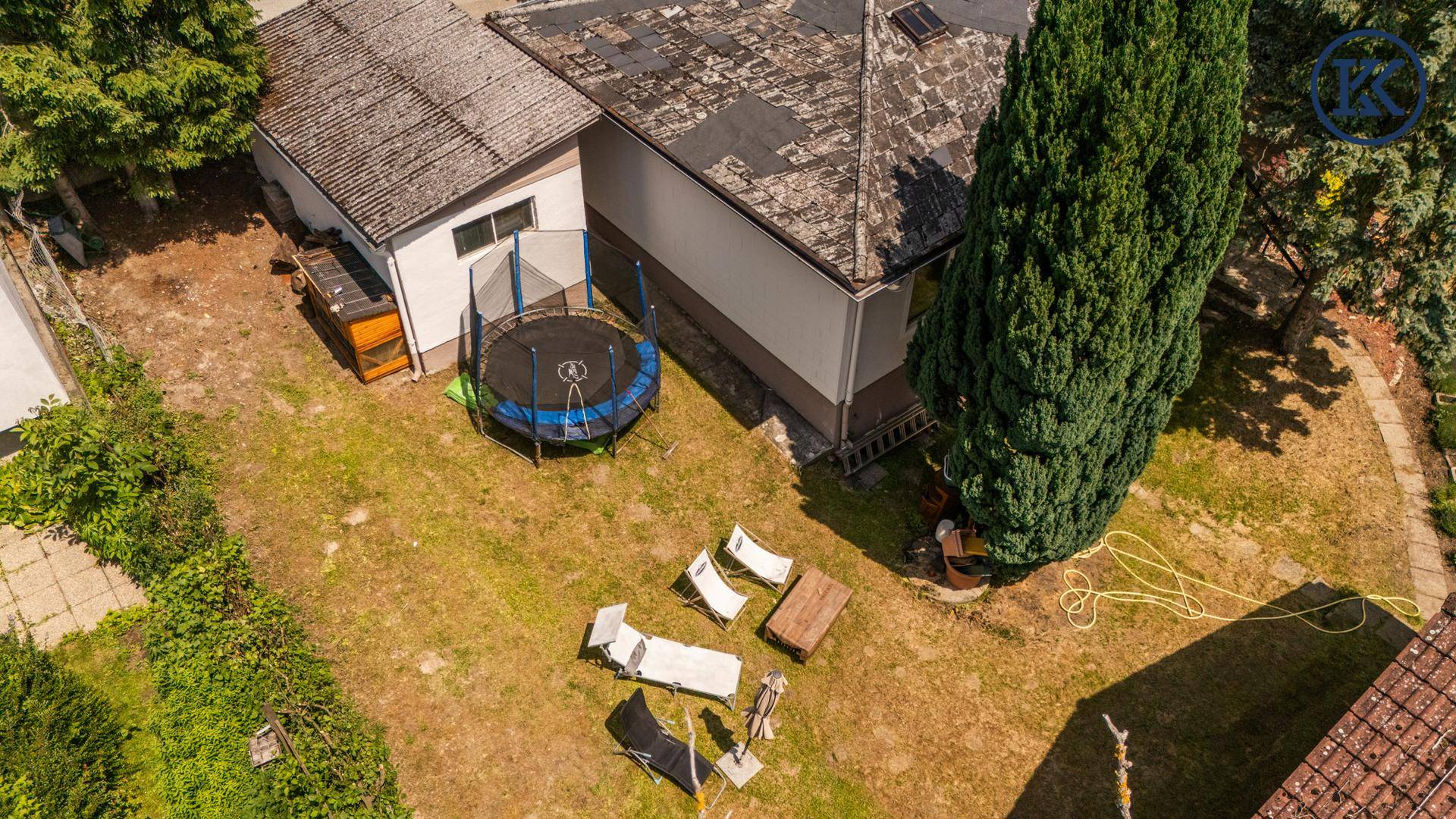Gartenbereich mit Rasenfläche, Trampolin und Liegestühlen neben dem Haus.