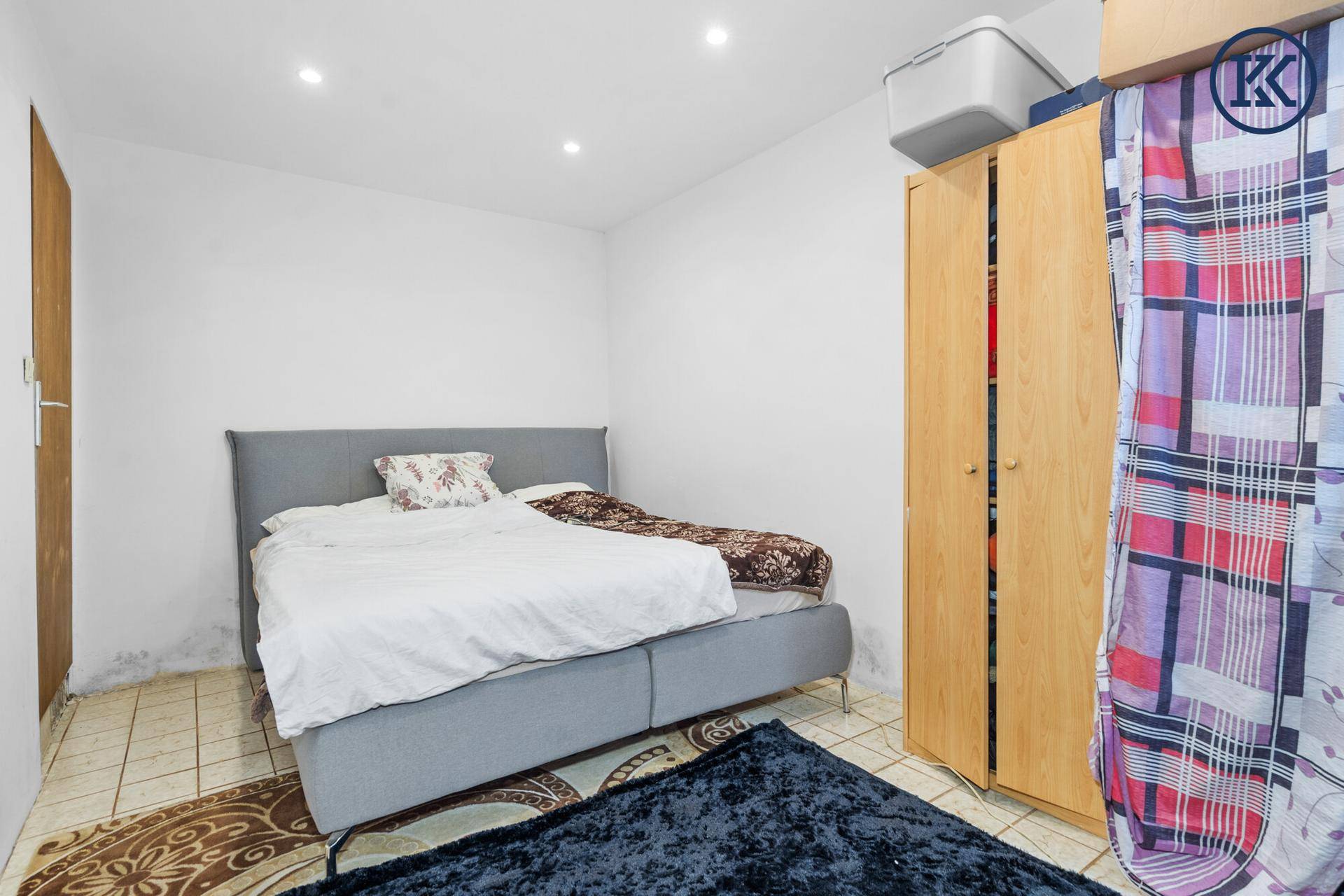 Schlafzimmer mit Doppelbett und Kleiderschrank, ausgestattet mit Fliesenboden.