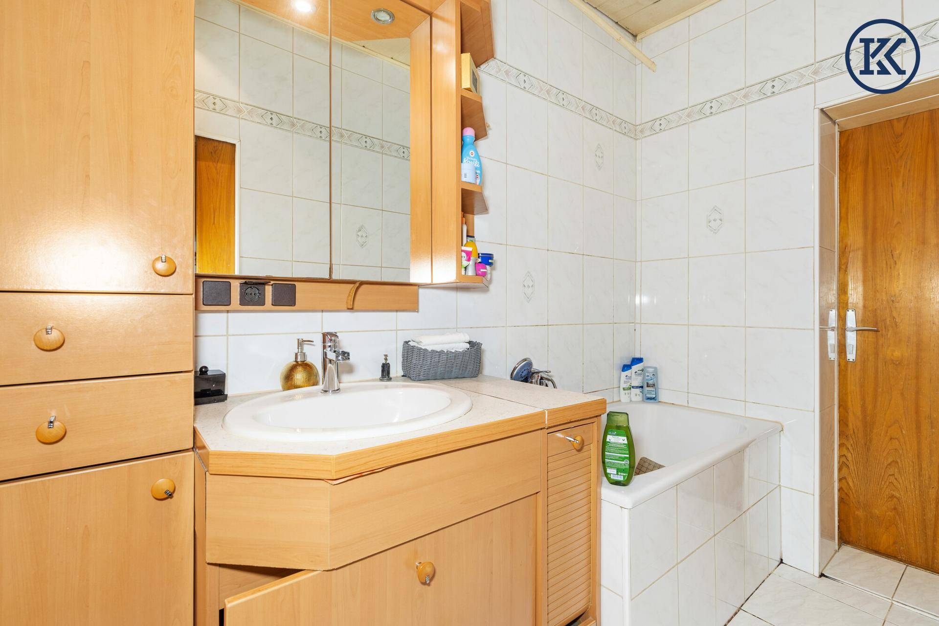 Badezimmer mit Badewanne, Waschbecken und Spiegelschrank, in einem funktionalen Zustand.