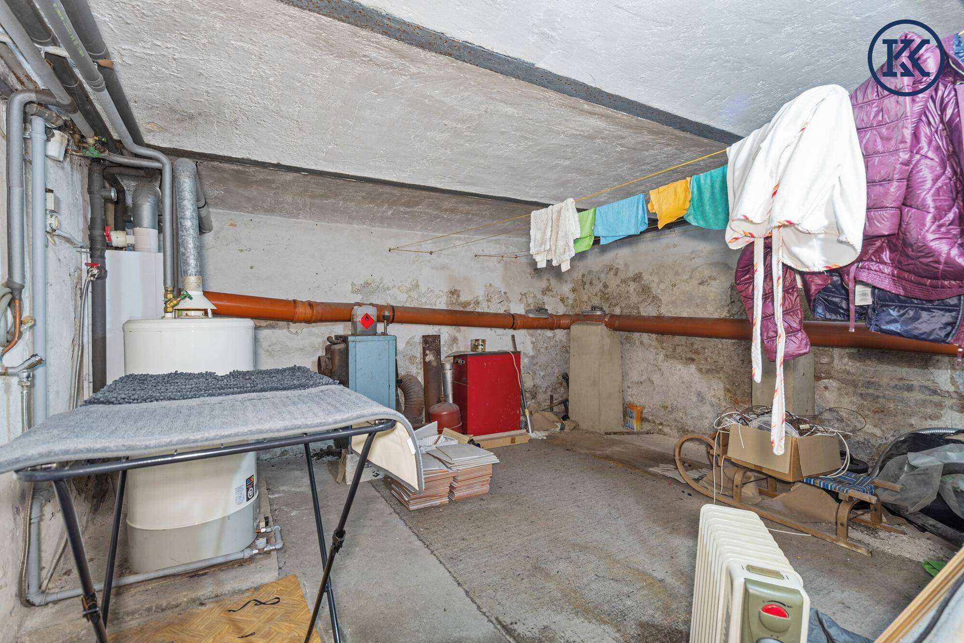Kellerraum mit Warmwasserbereiter, Wäscheleine und weiteren Lagerbereichen.