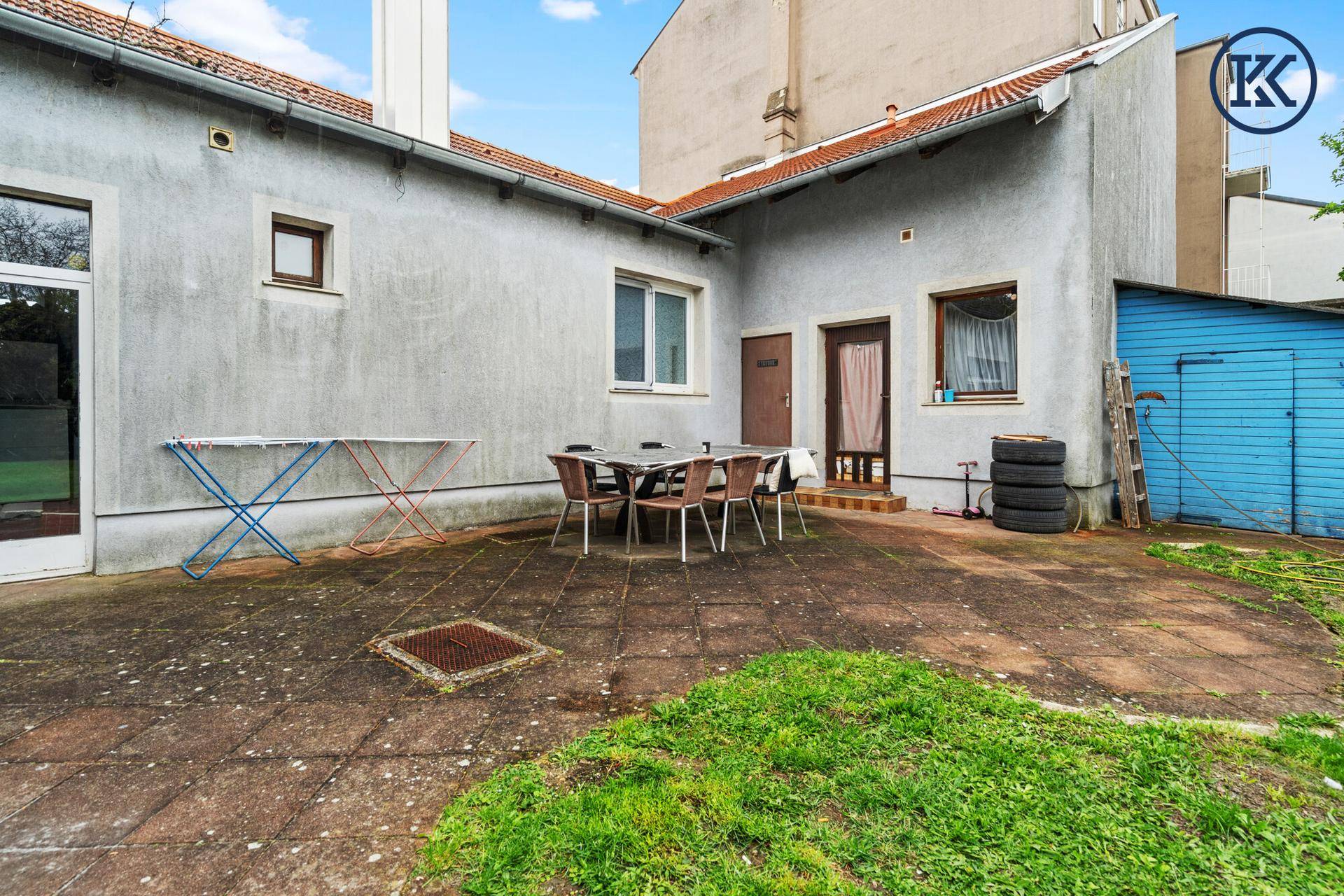 Gepflasterte Terrasse hinter dem Haus mit Gartenmöbeln für entspannte Stunden im Freien.