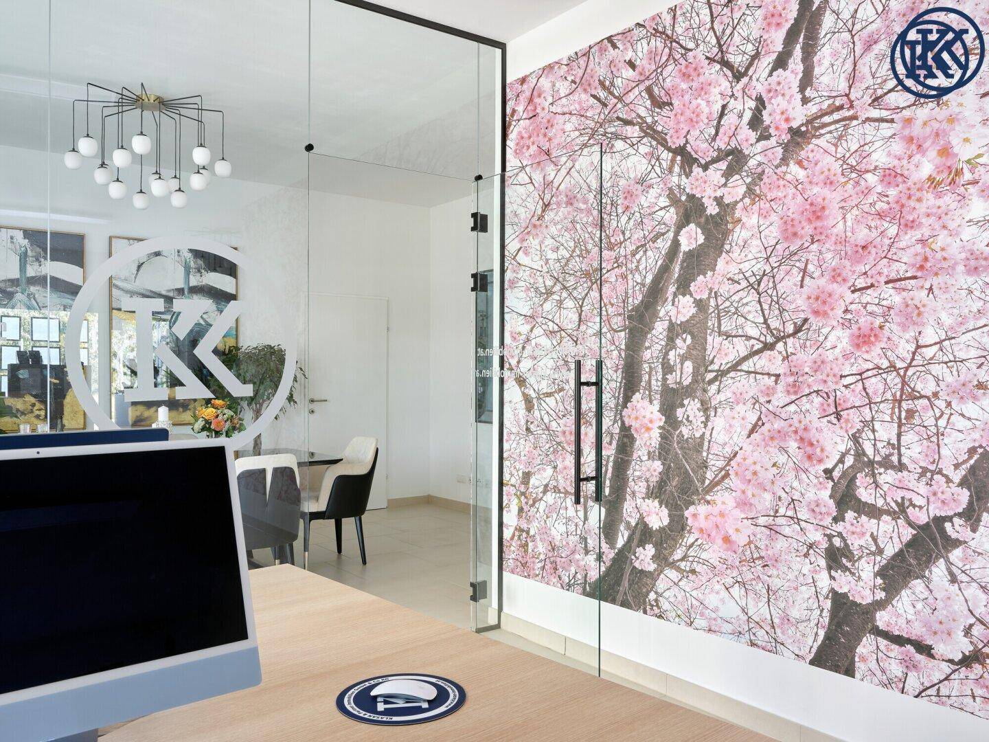 Bürobereich mit Schreibtisch und Blick auf eine Kirschblüten-Tapete und den Konferenzraum.
