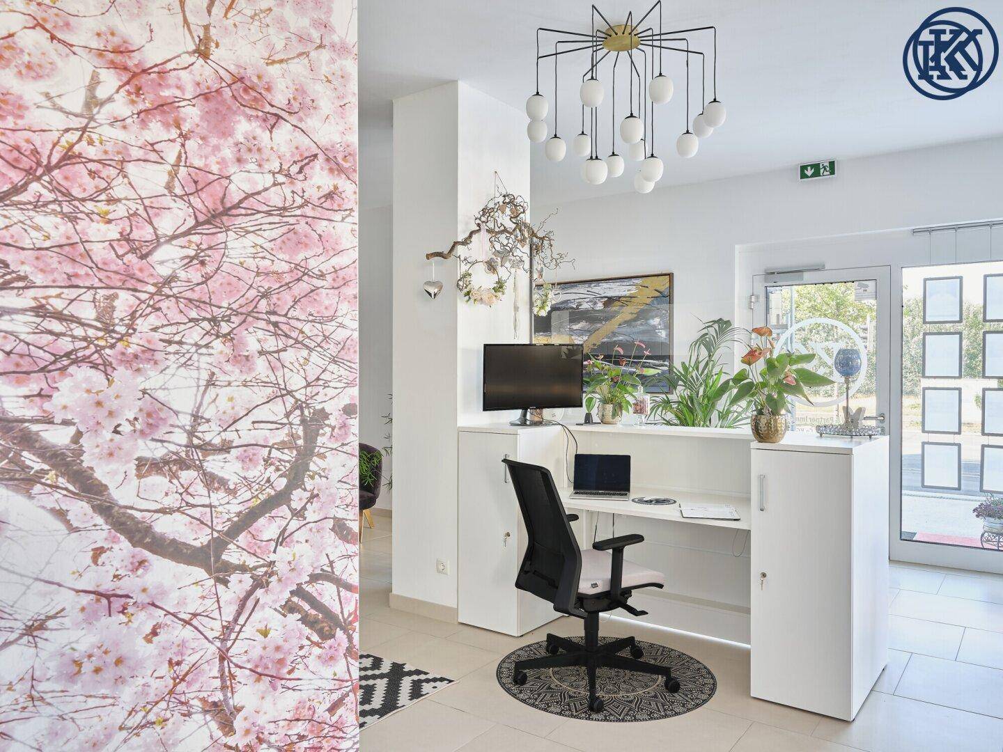 Empfangsbereich mit Schreibtisch, Kirschblüten-Tapete und moderner Deckenleuchte.