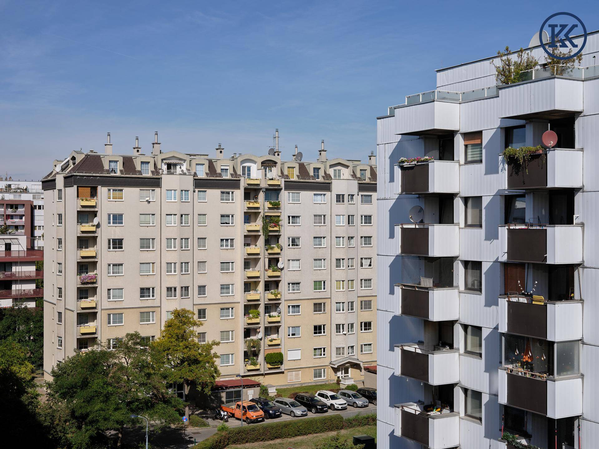 Mehrere Wohngebäude mit Balkonen und Parkplätzen in einer städtischen Umgebung.