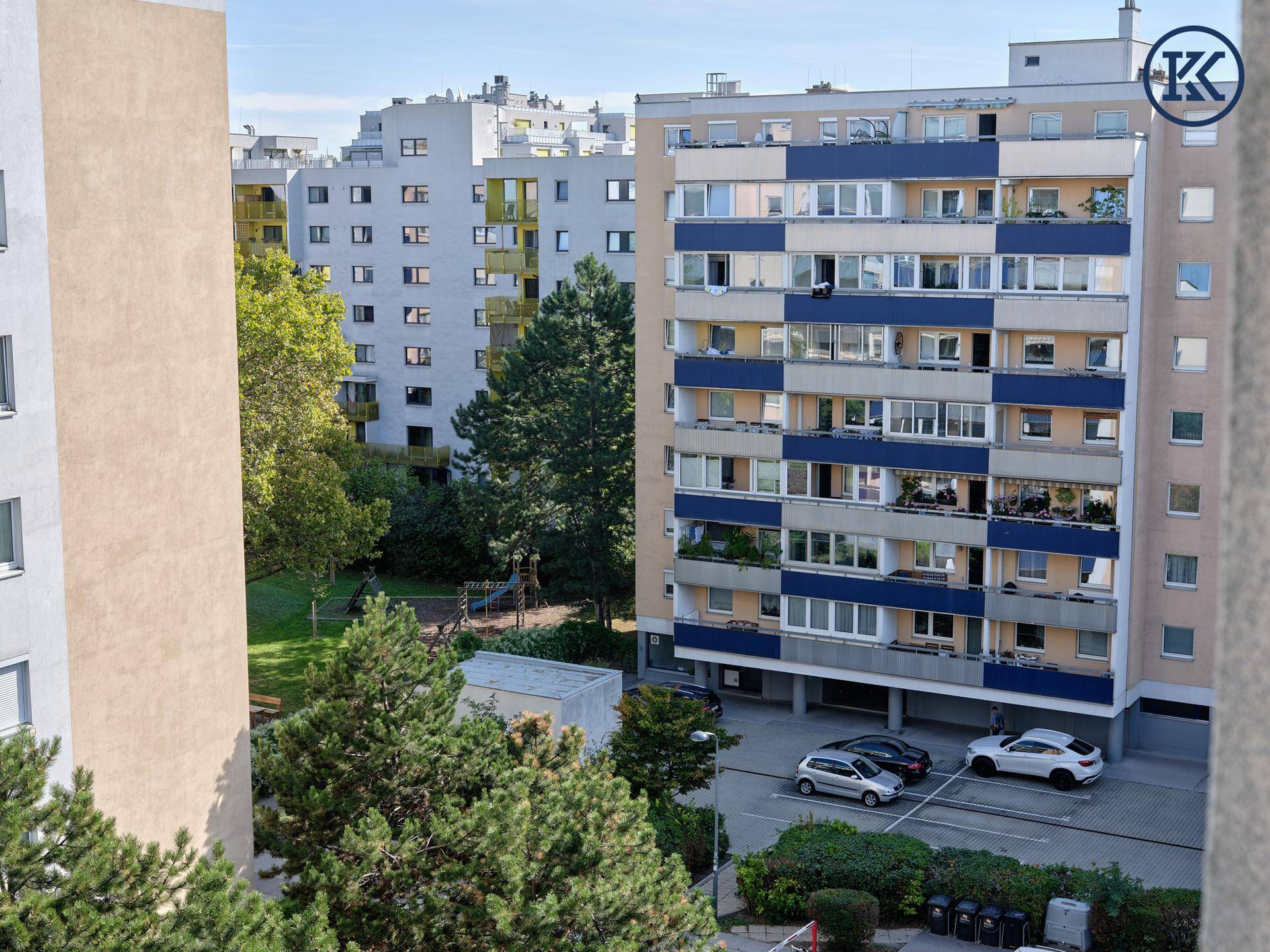 Wohngebäude mit blauer Fassade, Balkonen und einem Spielplatz im Vordergrund.