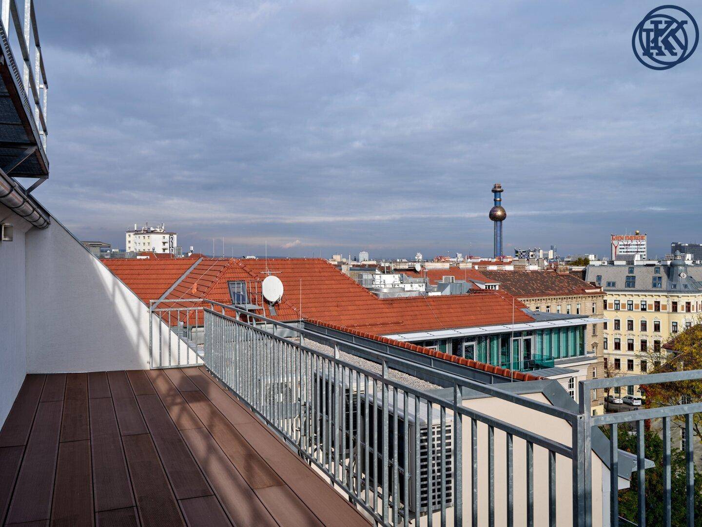 Moderne Dachterrasse mit Holzboden und weitem Blick über die Stadt und ihre markanten Gebäude.