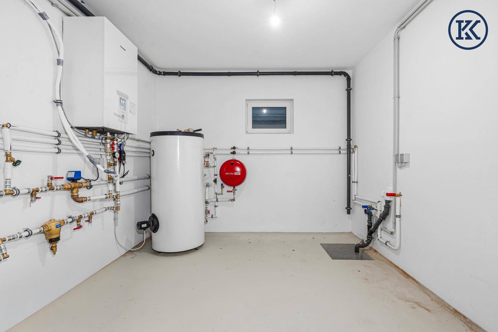Technikraum im Keller mit Heizungsanlage, Warmwasserspeicher und zahlreichen Leitungen.
