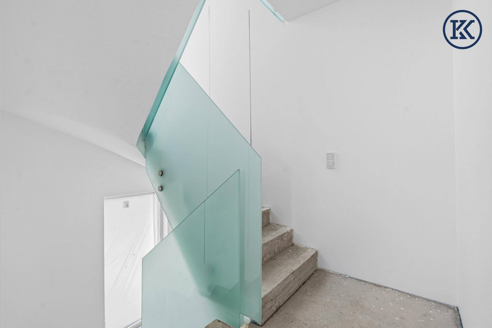 Moderner Treppenaufgang im Rohbau mit eleganter Glasbrüstung und Betonstufen.