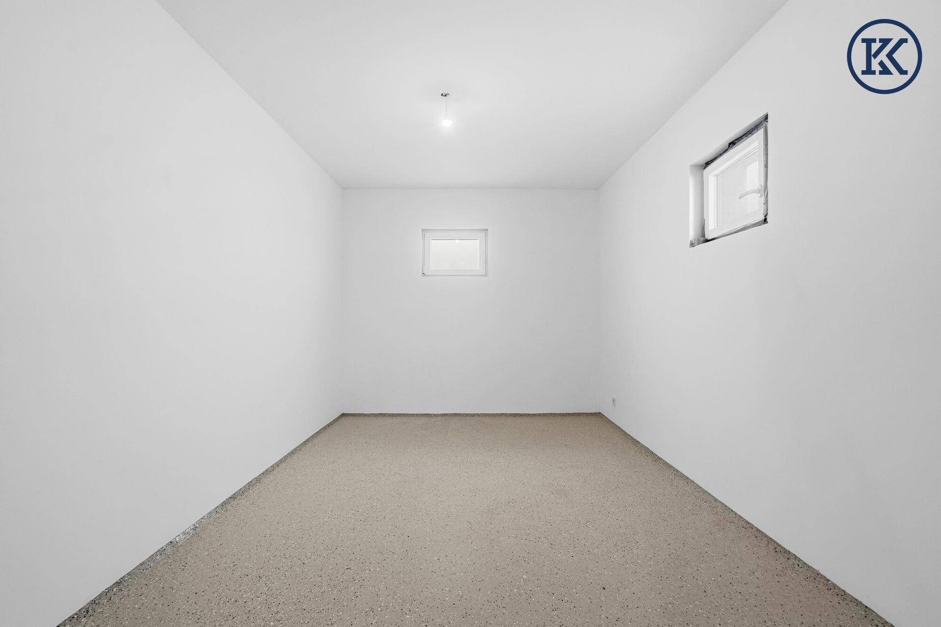 Heller Kellerraum im Rohbau mit zwei Fenstern, bereit für individuelle Nutzung.