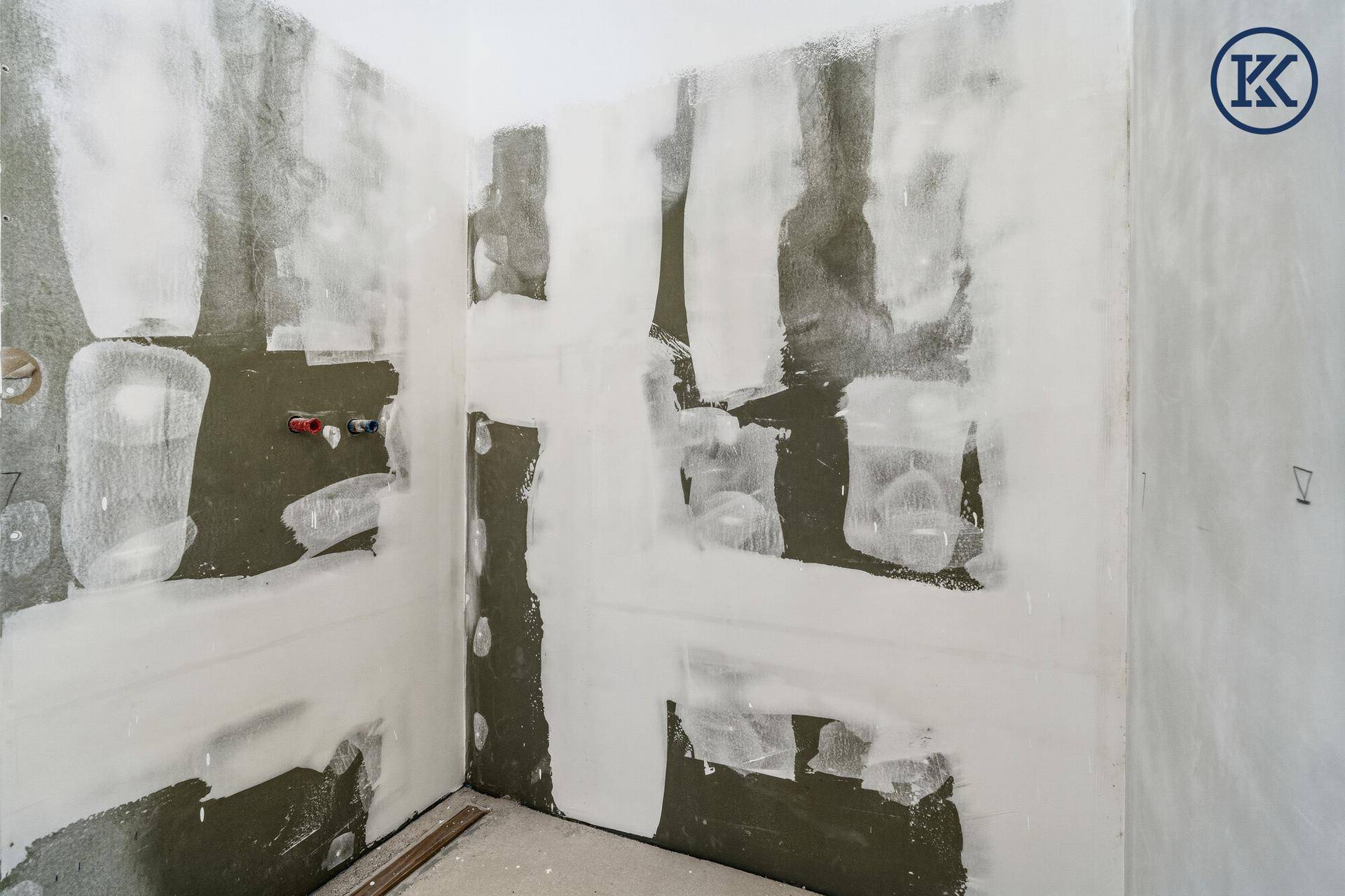 Badezimmer im Rohbau mit vorbereiteten Wänden für Fliesen und Installationen.